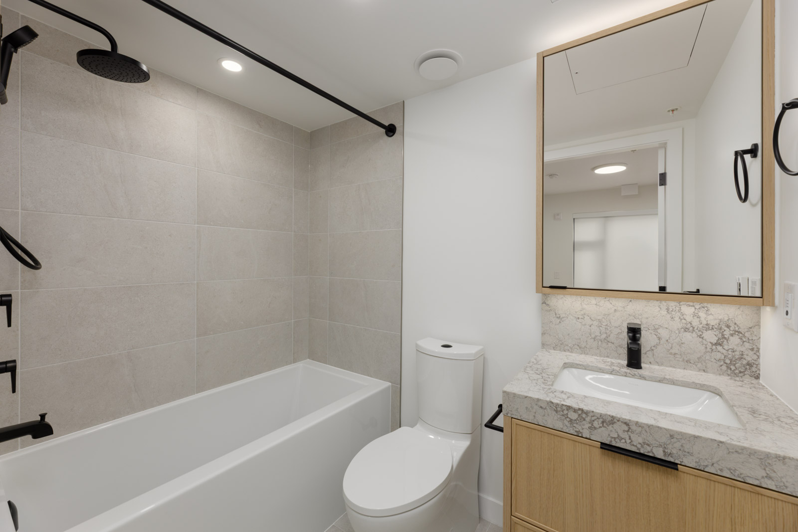 Bathroom at 5433 Oak Street with a bathtub, shower, toilet, and vanity featuring a stone countertop and mirror.