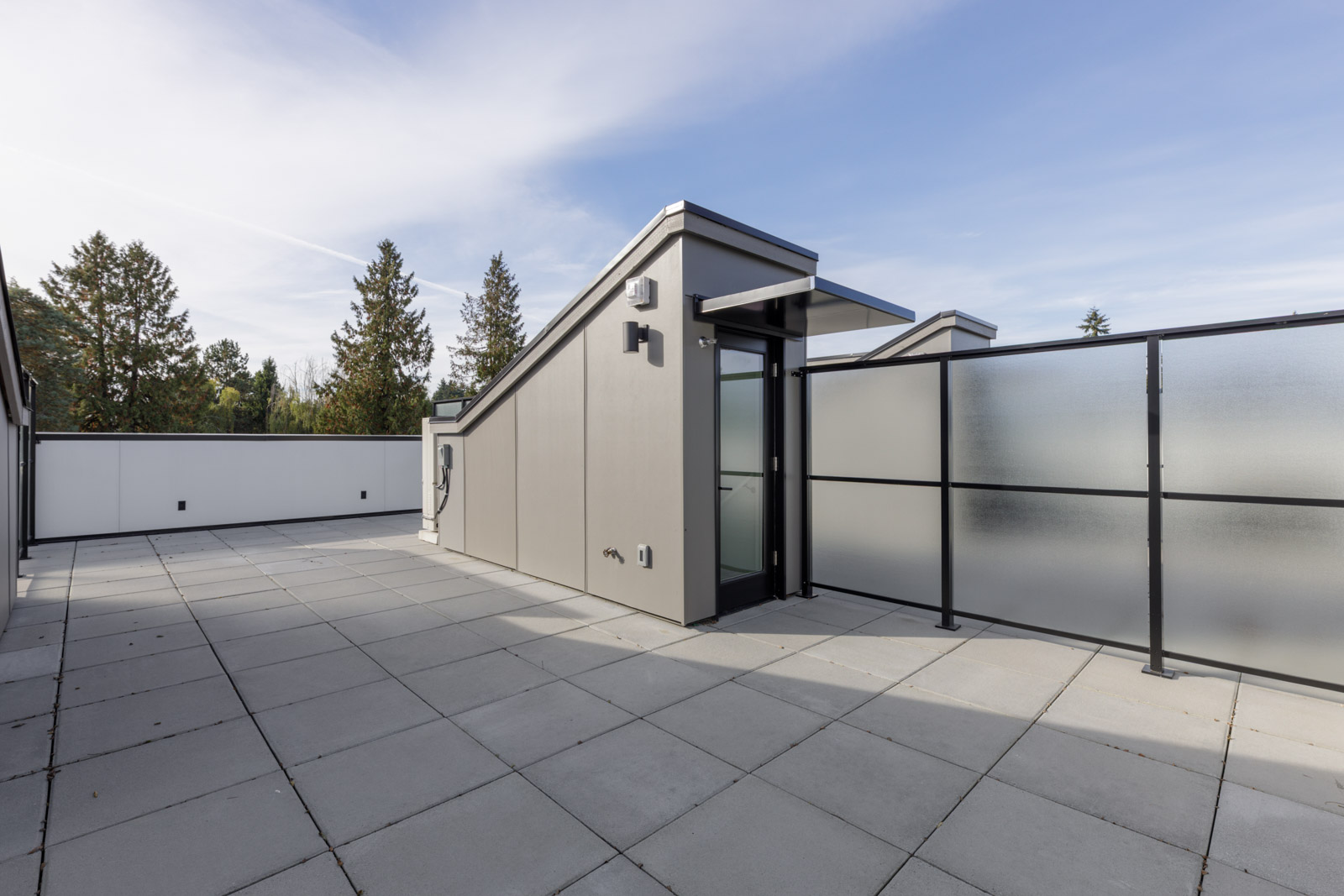Rooftop terrace at 5433 Oak Street with gray concrete tiles, a glass door, and frosted privacy screens.