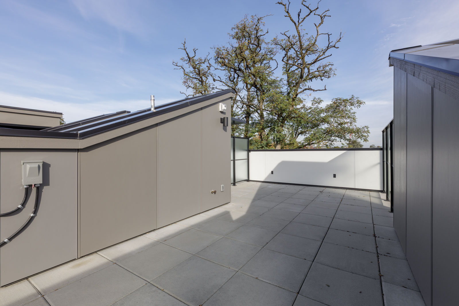 Rooftop terrace with gray tile flooring and glass railings at 5433 Oak Street, Vancouver.