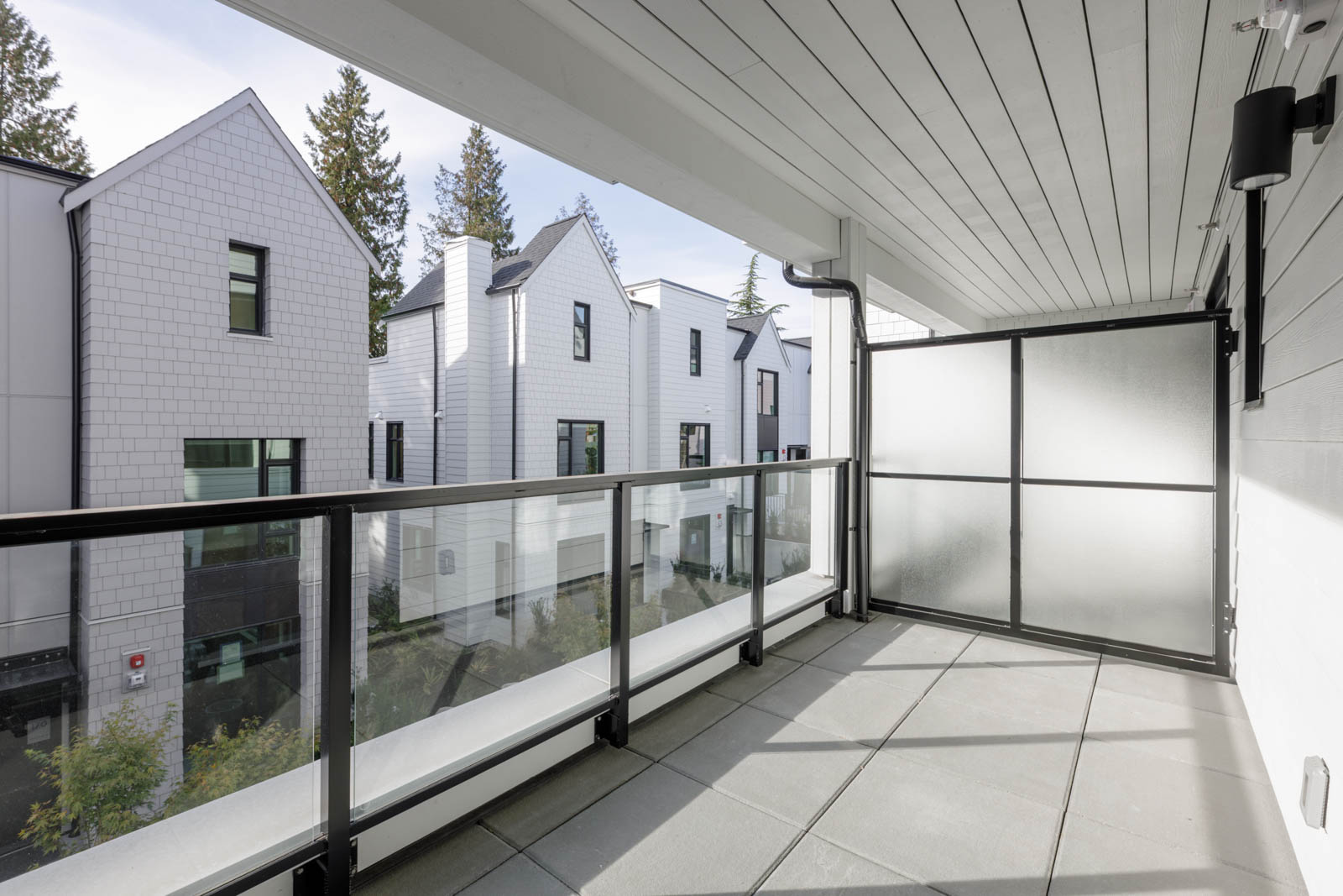 Glass balcony railing overlooking a row of modern white townhouses at 5433 Oak Street.
