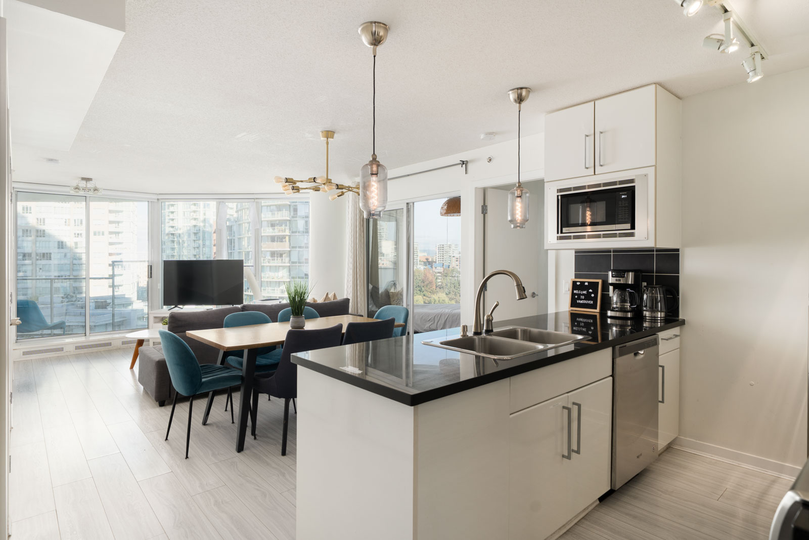 Modern kitchen with a black island at 689 Abbott Street, opening to a dining area and living room with a city view.