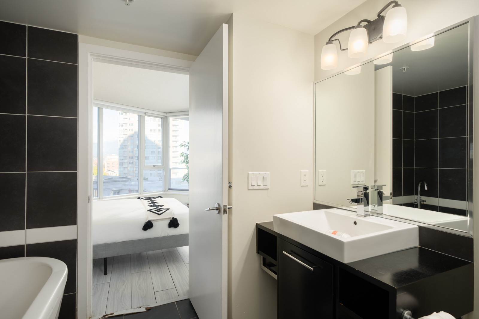 Bathroom vanity and sink at 689 Abbott St, Vancouver, with a partial view of a bedroom through the open doorway.