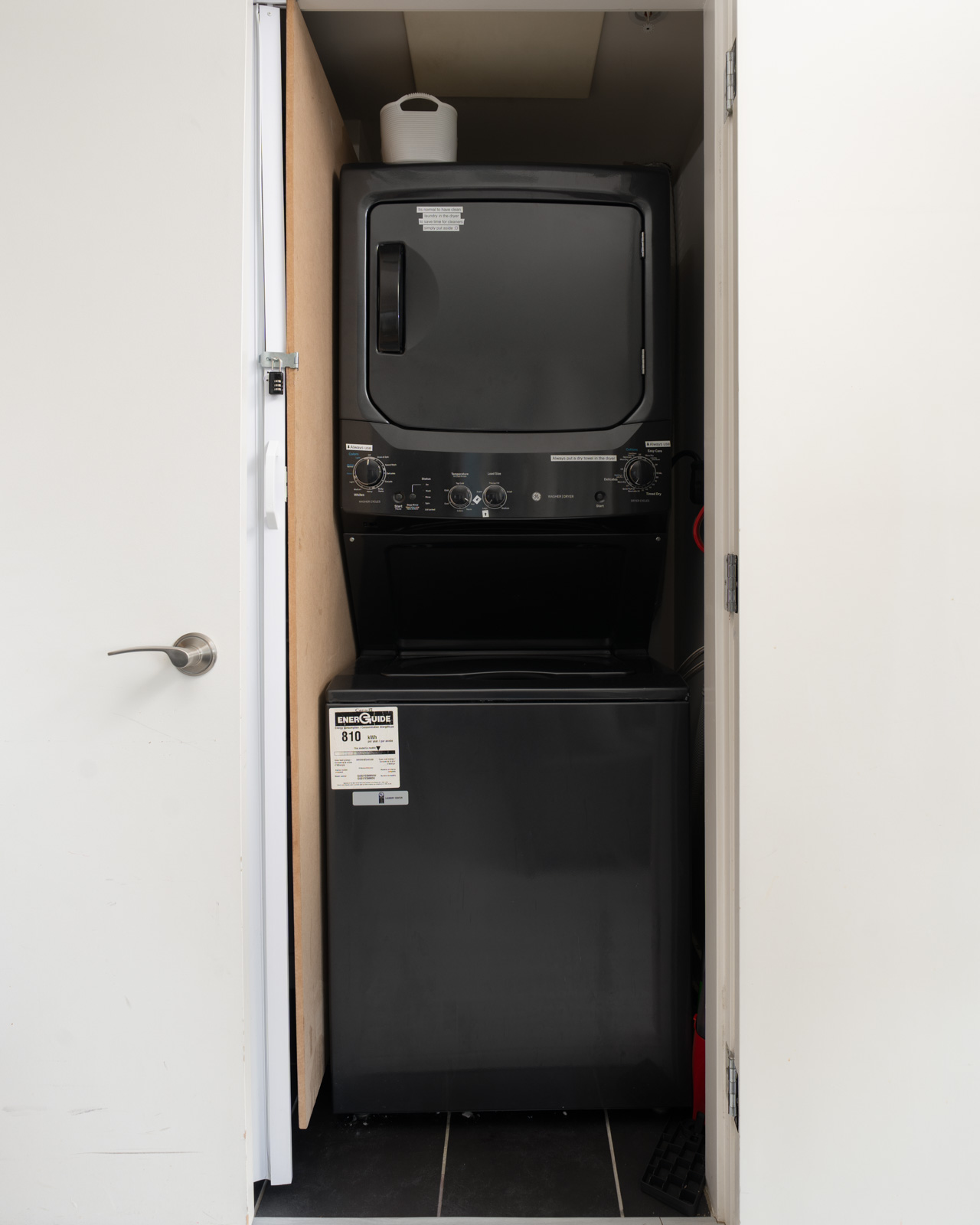 Black stacked washer and dryer unit inside a closet in a Vancouver apartment.