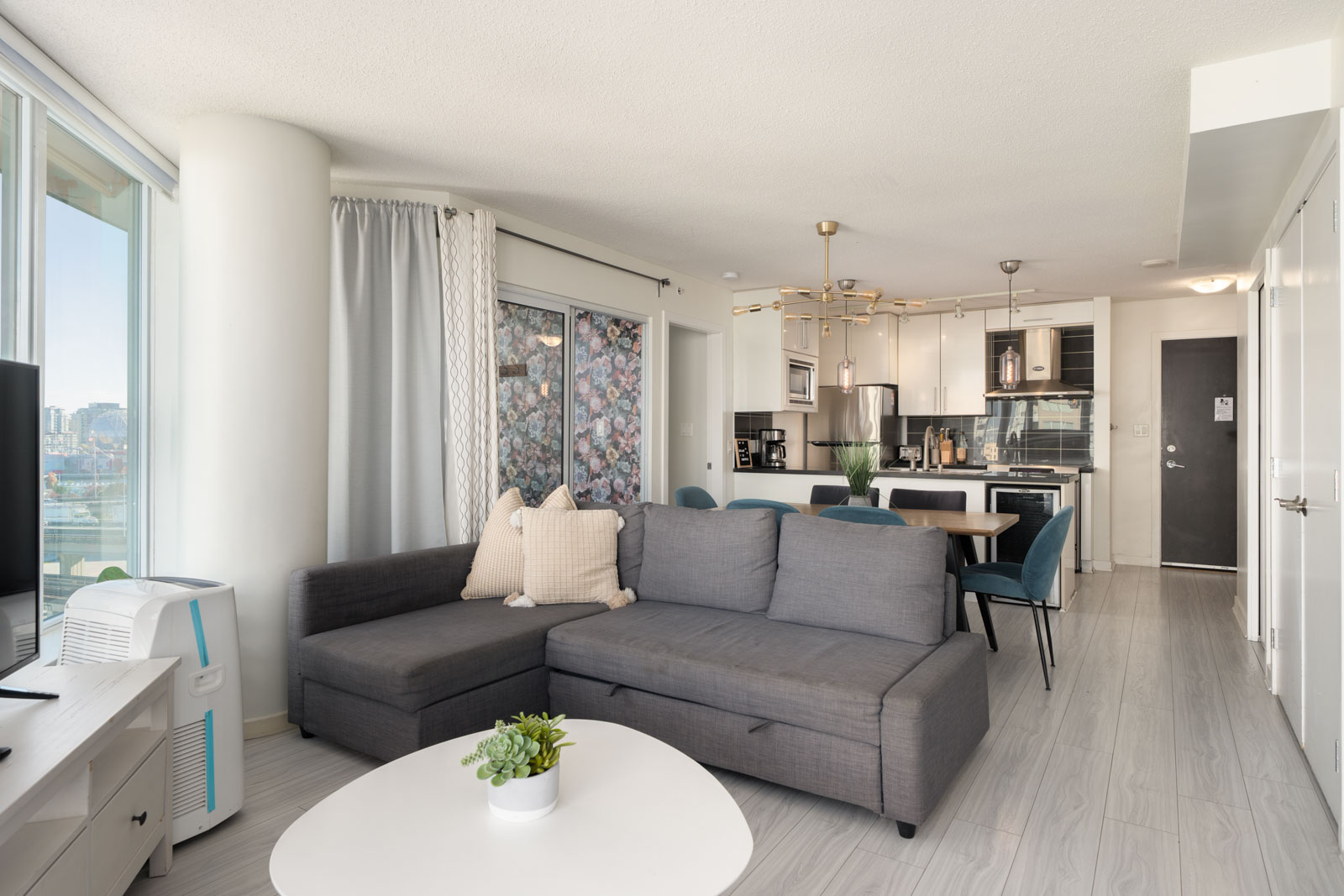 Open-concept living room at 689 Abbott St featuring a grey sectional sofa, white coffee table, and an adjoining kitchen.