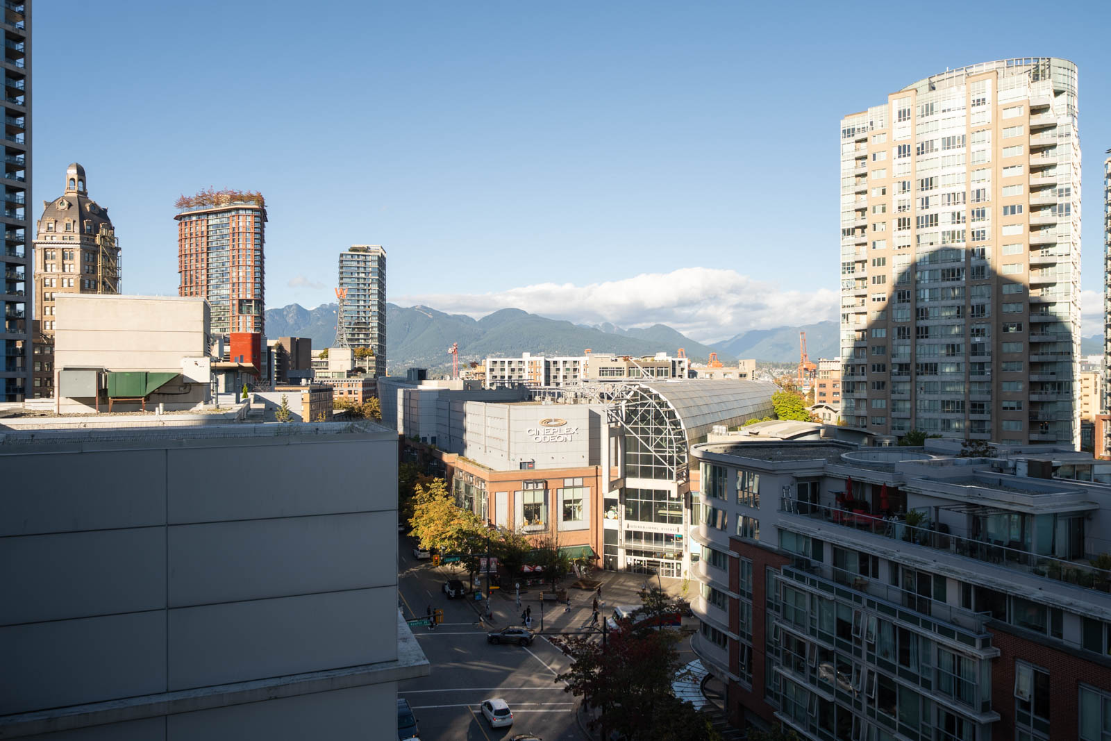Cineplex Odeon cinema on a city street at 689 Abbott St, surrounded by high-rises with mountains in the background.