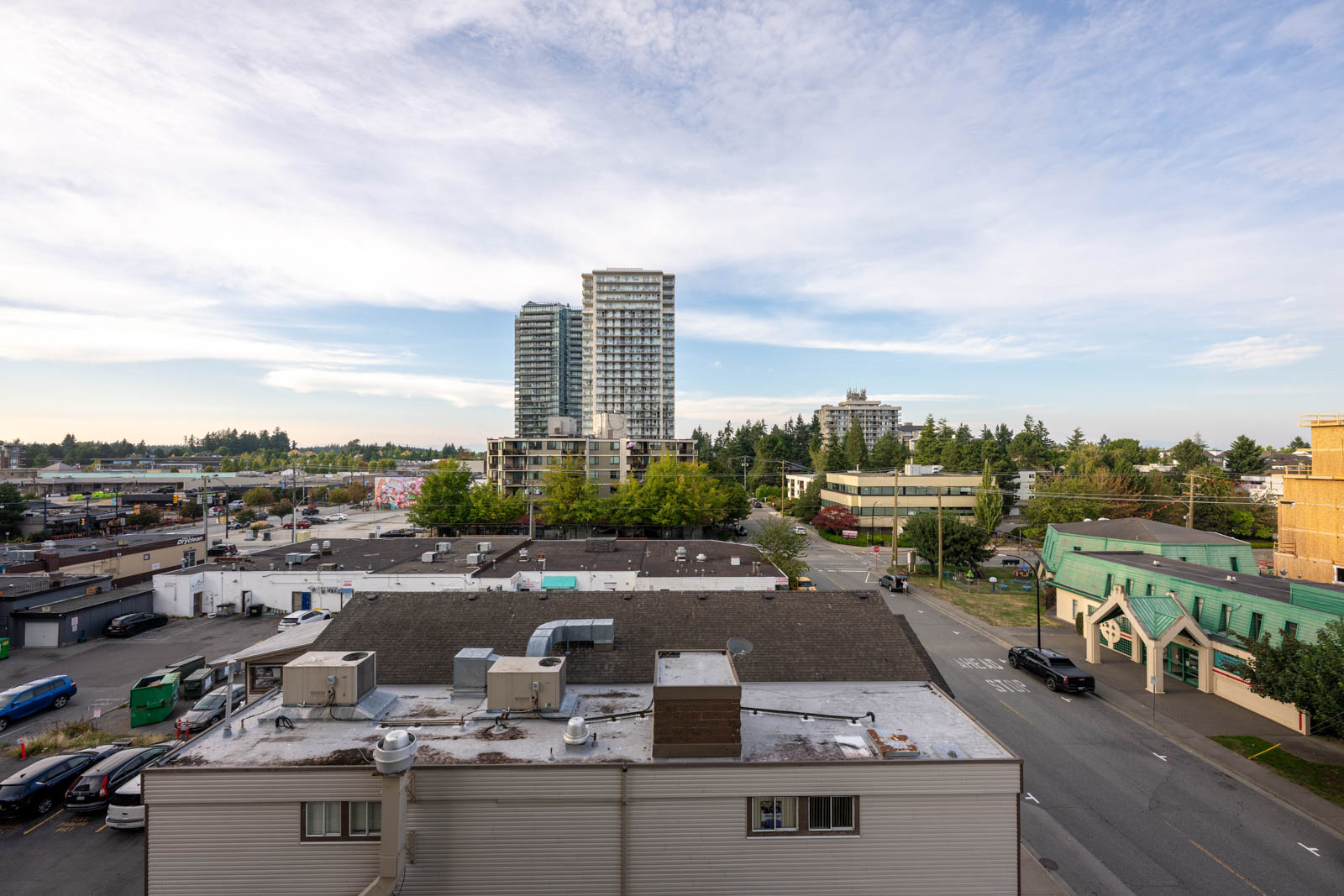 Elevated 7th-floor view of a street, low-rise commercial buildings, and two tall residential towers in White Rock.