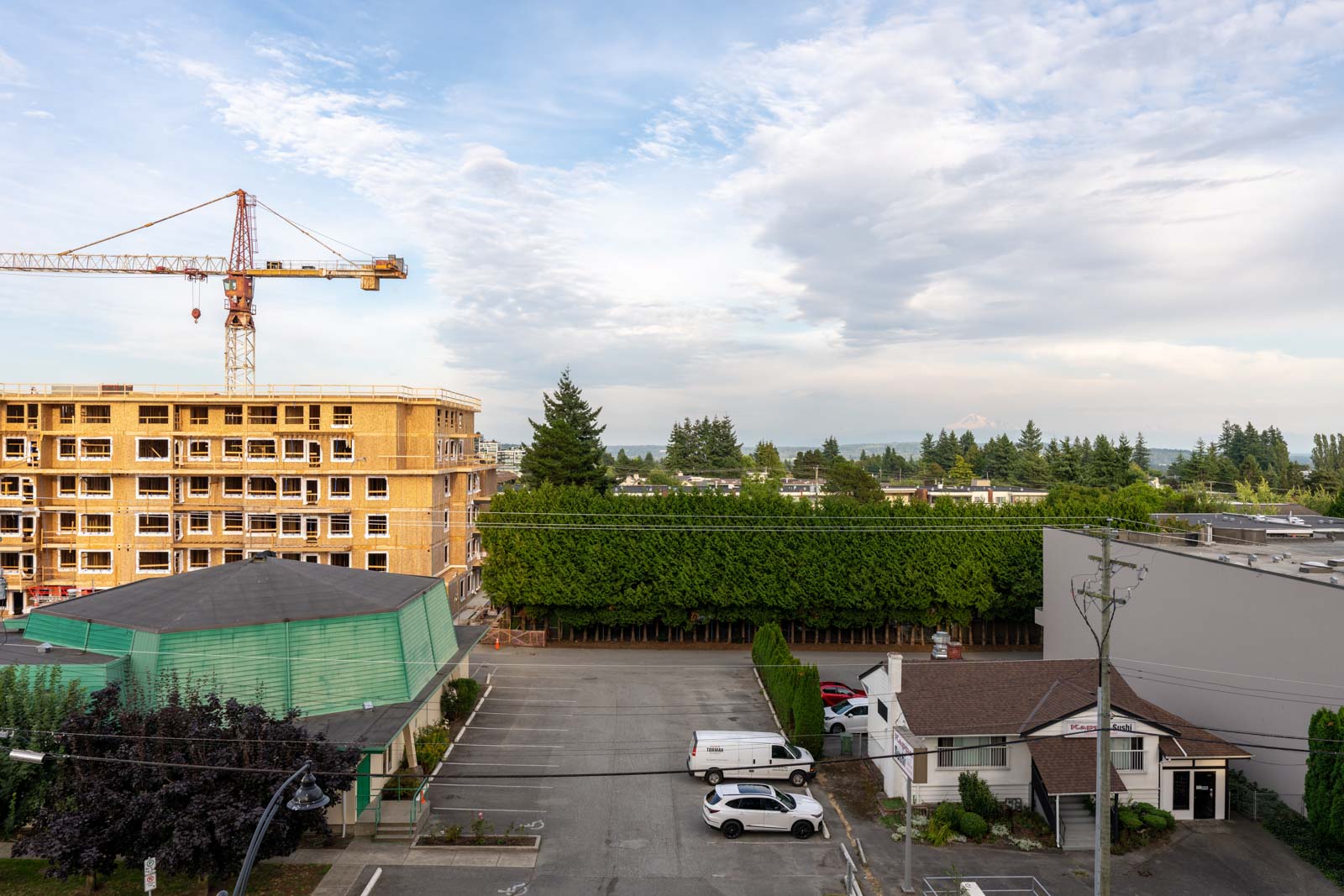 Elevated view of a parking lot at 1455 George Street, White Rock, between a building under construction and a retail shop.
