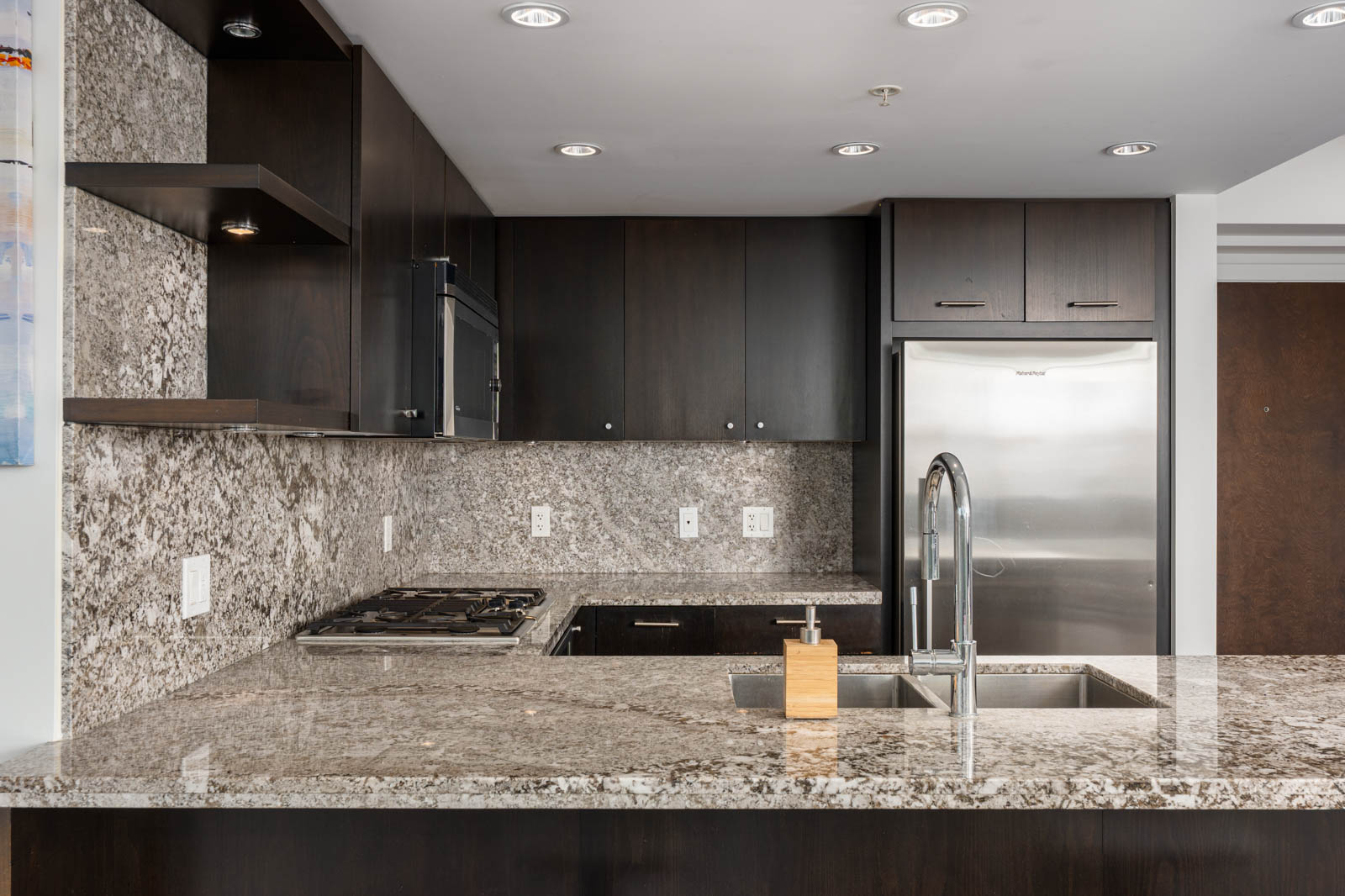 Modern kitchen at 1455 George Street featuring dark wood cabinets, granite countertops, and stainless steel appliances.