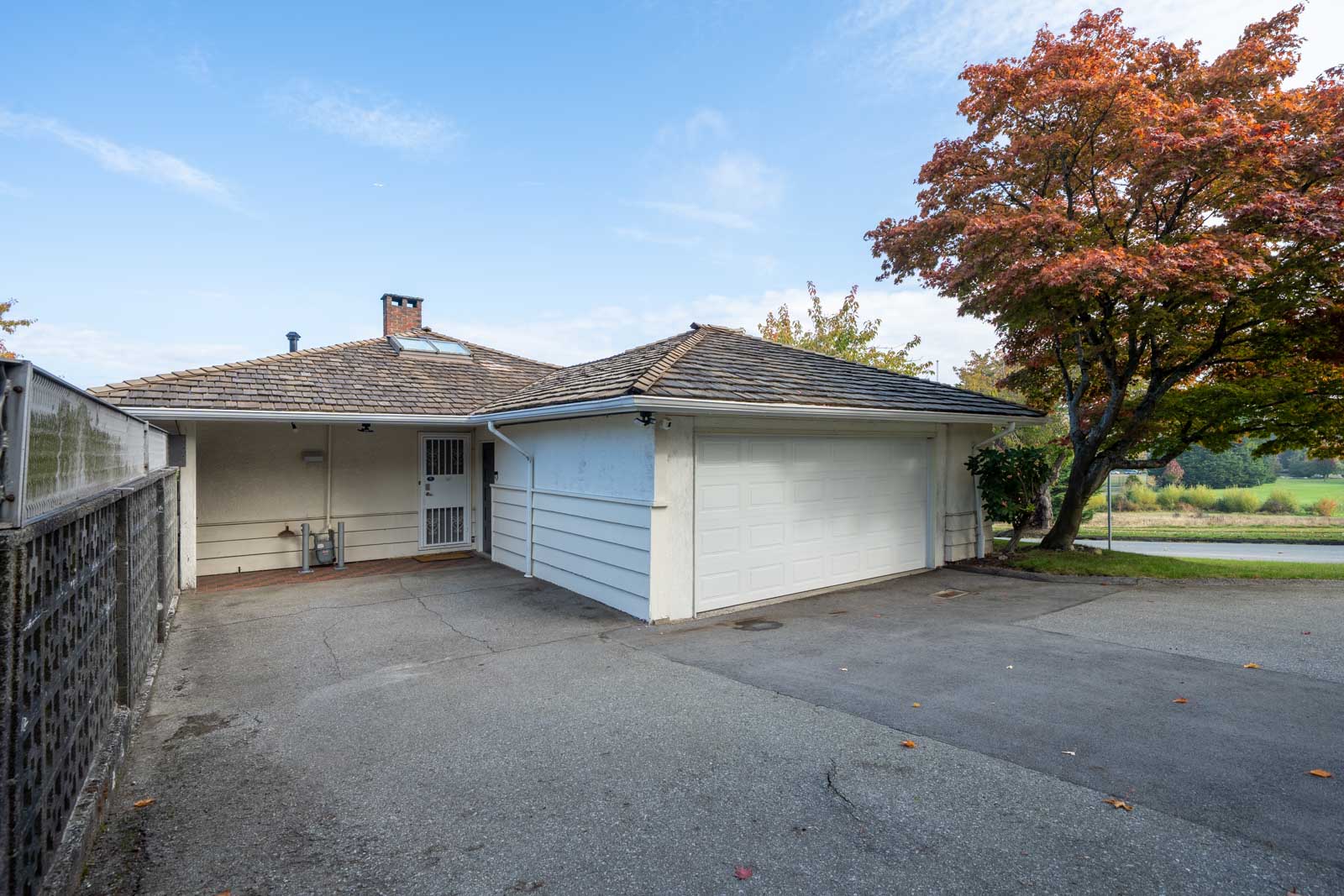 A white house on Haggart Street featuring a garage, paved driveway, and a tree with autumn foliage.