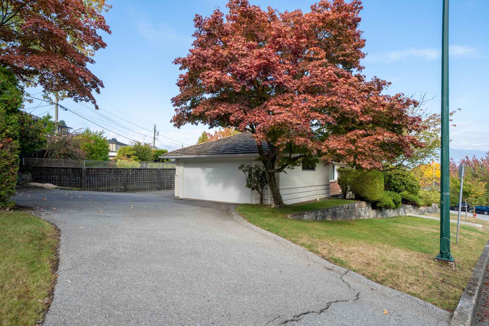 A driveway on Paton Street leads to a white detached garage, shaded by a large tree with red and green autumn leaves.