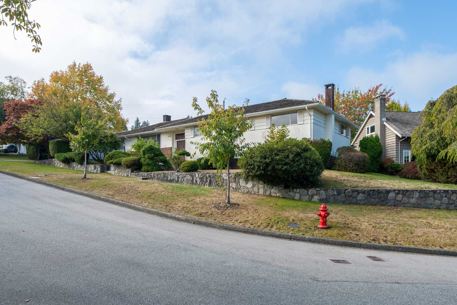 Single-story ranch on a sloped Vancouver basement lot with a stone retaining wall and a red fire hydrant on Paton Street.