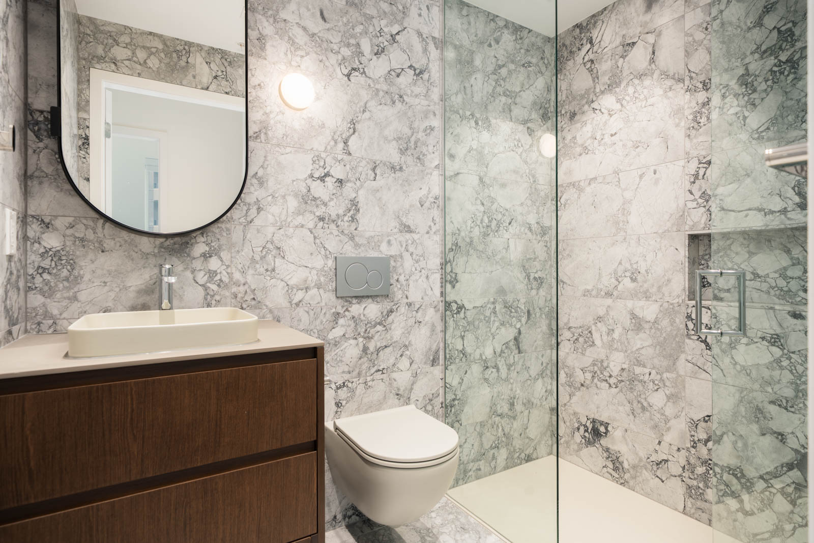 Modern bathroom at 1277 Hornby St with a wooden vanity, vessel sink, wall-mounted toilet, and glass-enclosed shower.