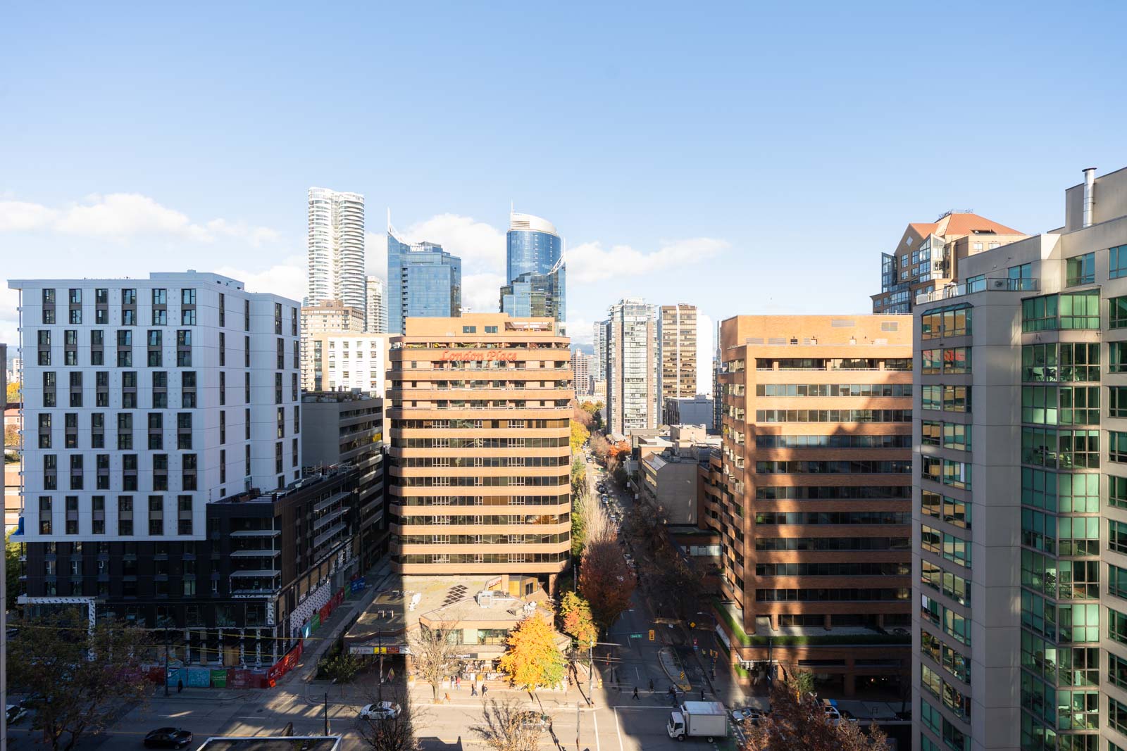 High-angle view of the street at 1277 Hornby St in Vancouver, nestled between two buildings under a clear blue sky.