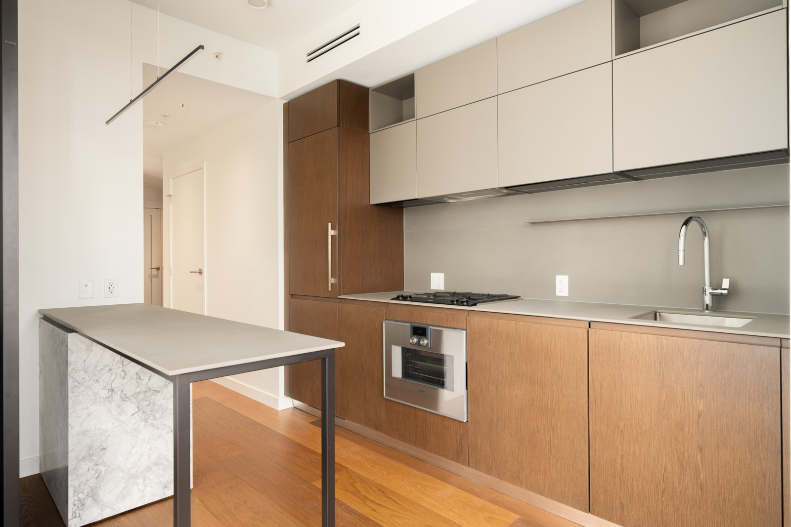 Modern kitchen with wood grain cabinetry, marble-patterned island, and built-in appliances at 1277 Hornby St, 14th floor.