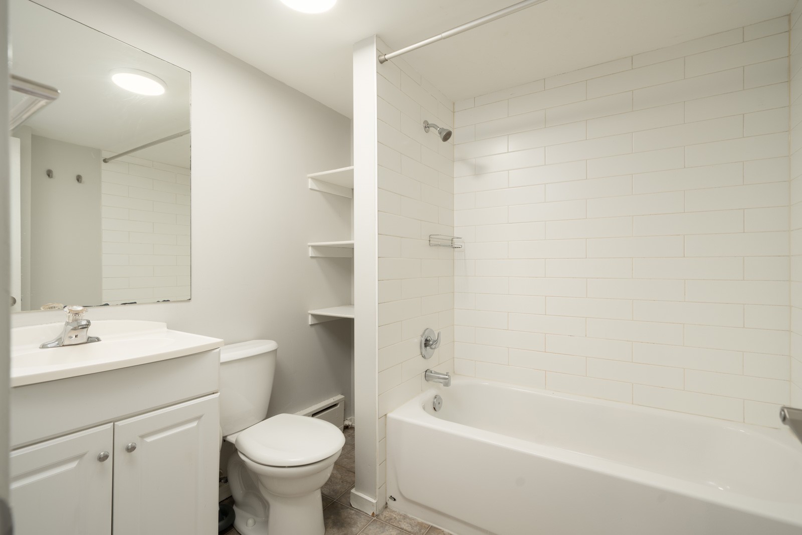 Bathroom with a white vanity, toilet, and bathtub with a white tiled shower surround at 1445 W 11th Ave.
