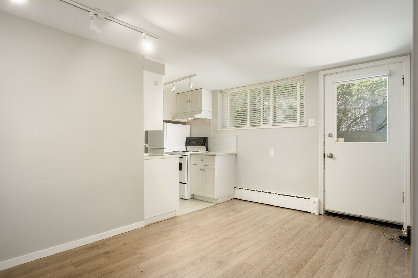 Small kitchen at 1445 W 11th Ave featuring white cabinets and appliances near a window with blinds and an exterior door.