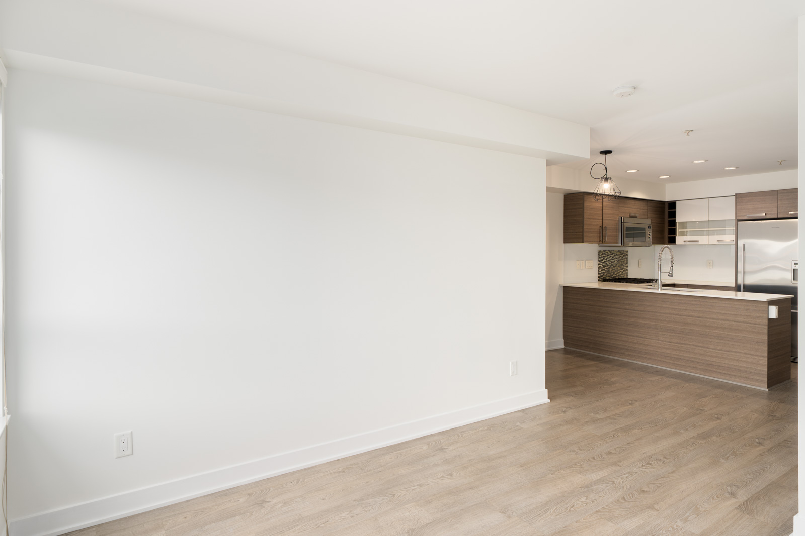 A large empty wall in a 3rd-floor office apartment on W 4th Ave, facing an open-concept kitchen.
