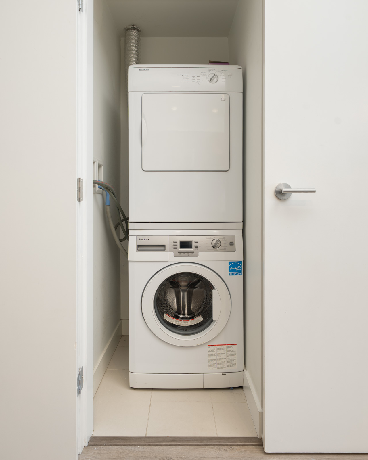 Stacked Blomberg washer and dryer in a small laundry closet at the 3rd floor office on W 4th Ave.