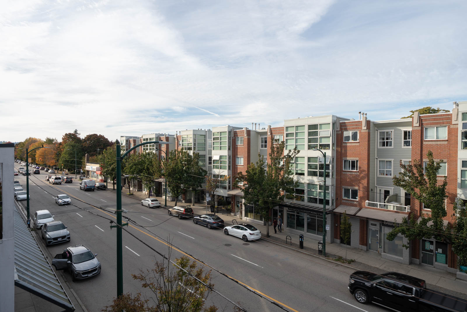 Elevated view of 2858 W 4th Ave, featuring brick and glass residential buildings, parked cars, and trees.