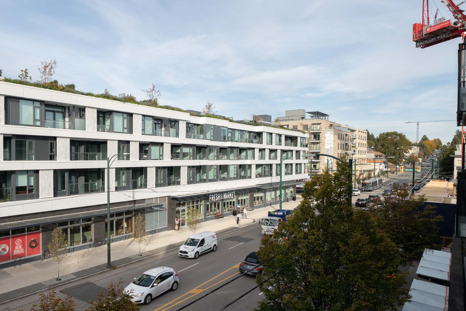 A multi-story apartment building at 2858 W 4th Ave with a ground-floor Fresh Street Market on a busy city street.