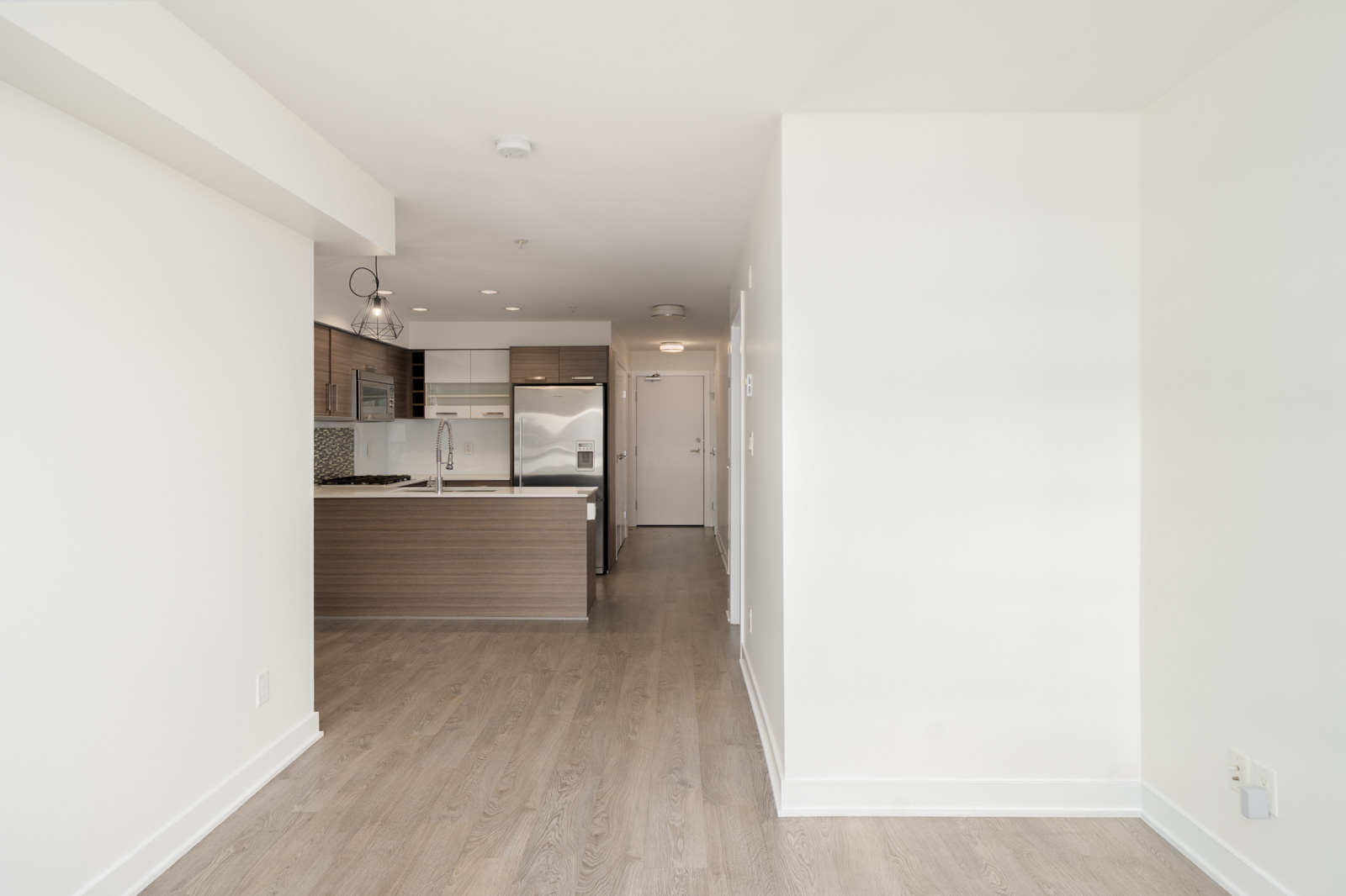 View from the open office at 2858 W 4th Ave toward a kitchen with dark cabinetry and stainless steel appliances.