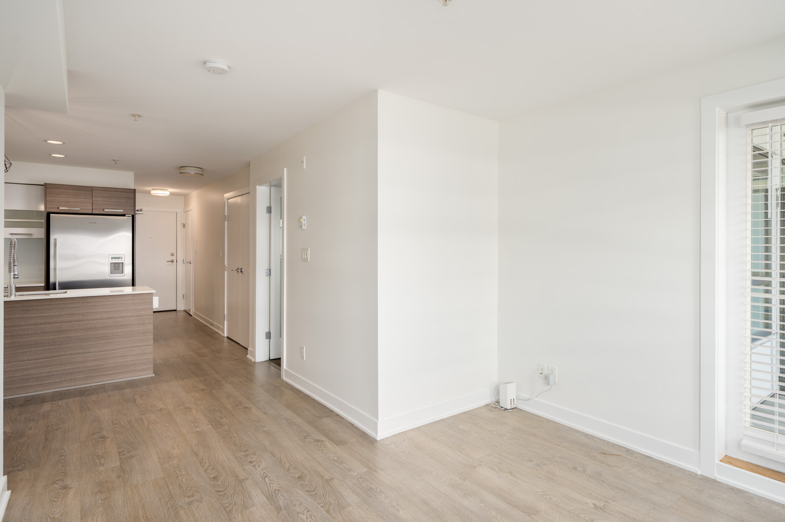 Open-plan interior at 2858 W 4th Ave featuring a wood-toned kitchen, light wood flooring, and a balcony glass door.
