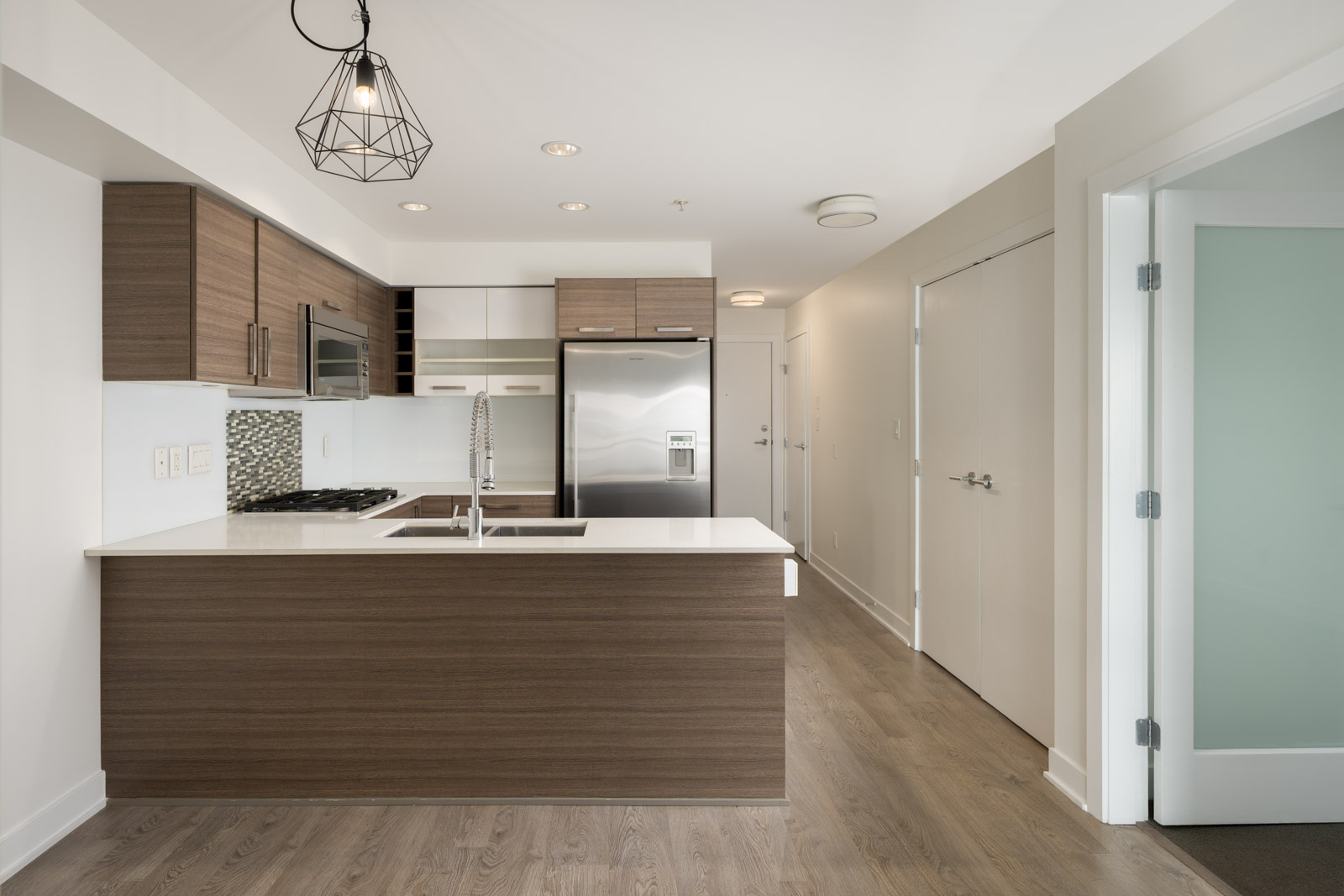 Modern kitchen with wood-finish cabinets, white counters, and stainless steel appliances at 2858 W 4th Ave, Vancouver.