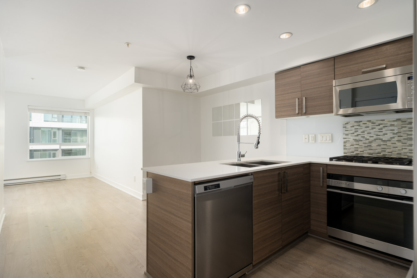 Modern kitchen with wood cabinets and stainless steel appliances at the 2858 W 4th Ave office, featuring a breakfast bar.