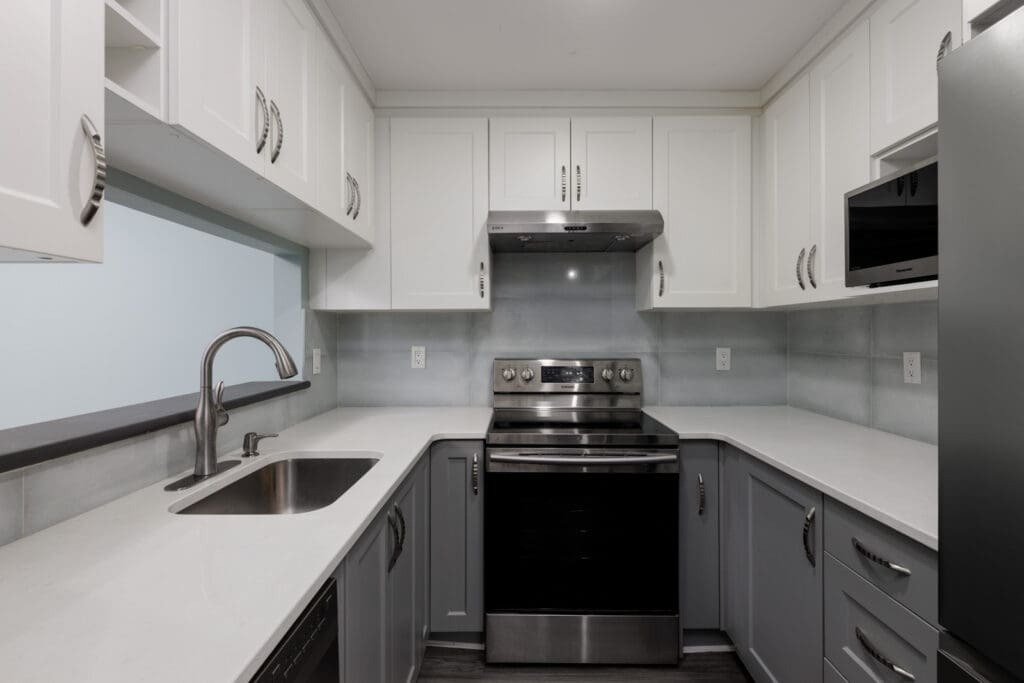 Modern kitchen on the 3rd floor at 2231 Welcher Ave, Port Coquitlam with white uppers, gray lowers, and stainless appliances.
