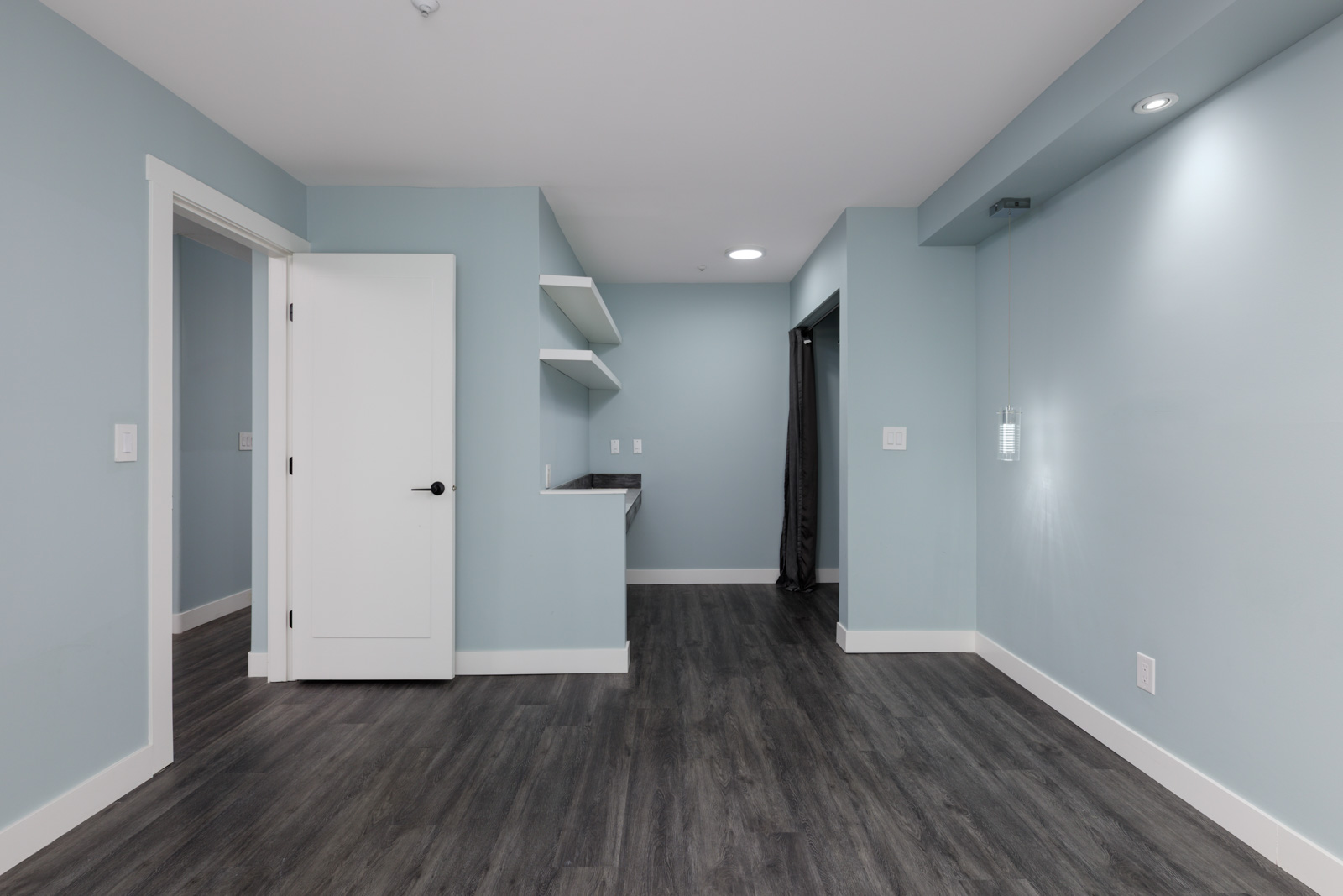 Empty modern room, 3rd floor at 2231 Welcher Ave, Port Coquitlam; light blue walls, white trim, dark wood floors, small kitchenette.