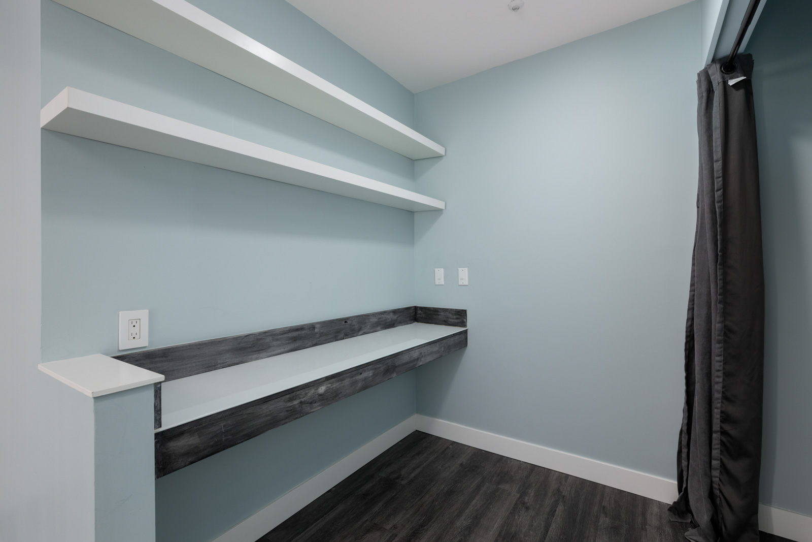 Small room on 3rd Floor, Welcher Ave, Port Coquitlam; light blue walls, white shelves, gray built-in desk, dark wood floors.