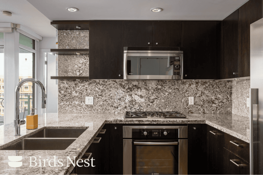 Modern kitchen at 1455 George Street with dark wood cabinets, speckled stone countertops, and stainless steel appliances.