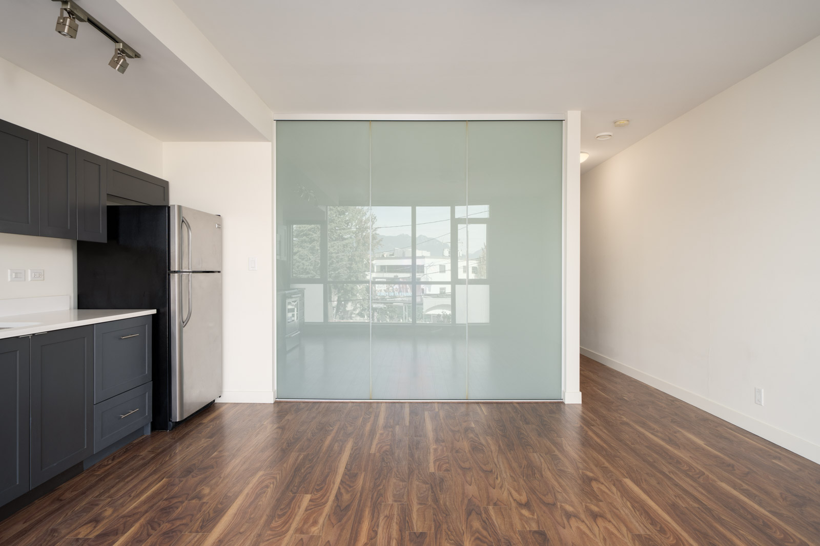 Kitchen at 2511 Quebec featuring dark gray cabinets, a stainless steel refrigerator, and a frosted glass sliding wall.