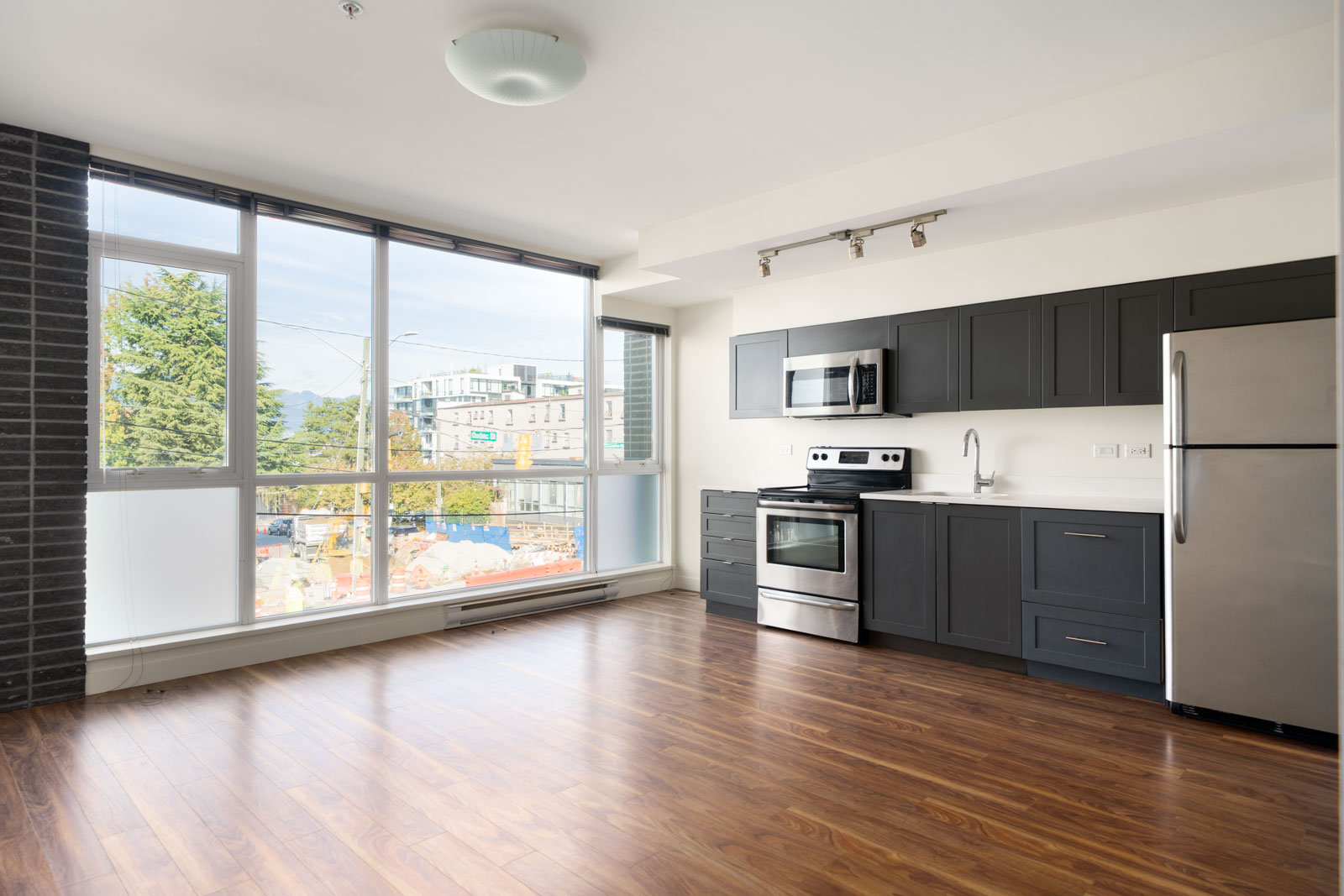 Modern kitchen at 2511 Quebec Street with dark cabinetry, stainless steel appliances, and windows overlooking the street.