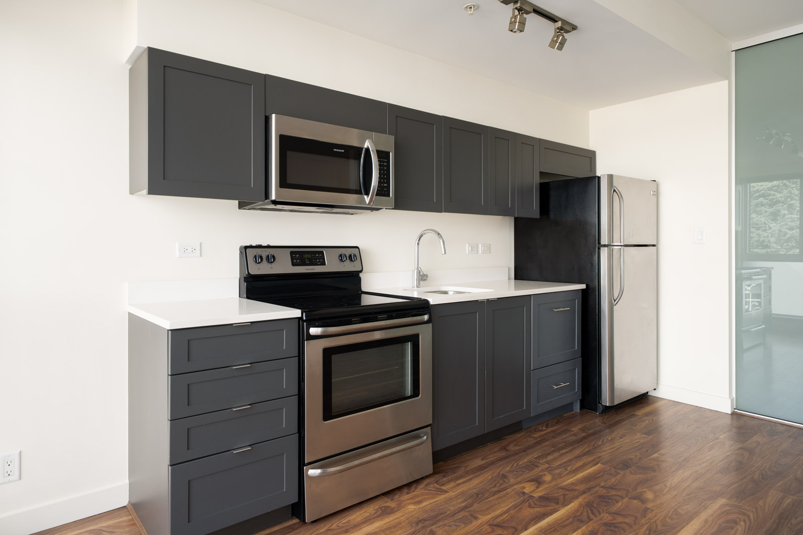 Kitchen with dark grey shaker cabinets, white countertops, and stainless steel appliances at the 2511 Quebec office.