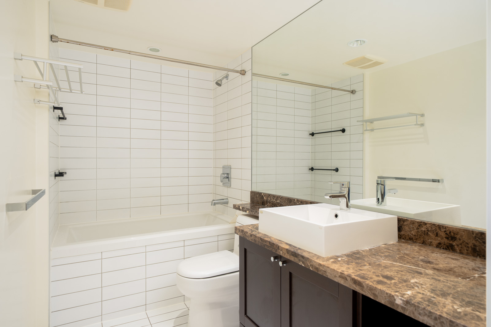 Bathroom at 4818 Eldorado Mews with white subway tile, a bathtub, a toilet, and a square vessel sink on a dark vanity.