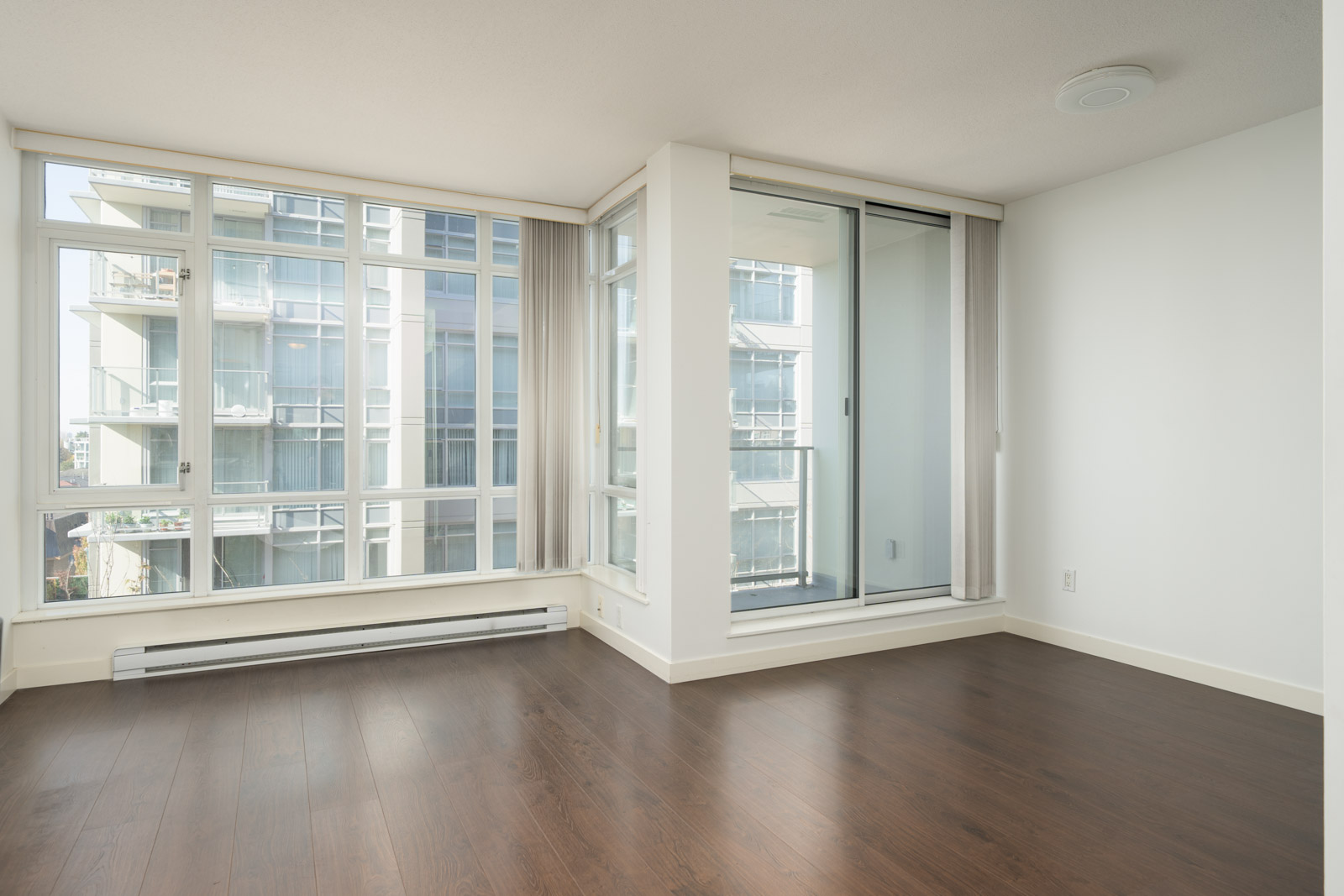 Empty room at 4818 Eldorado Mews featuring dark wood floors, floor-to-ceiling windows, and a balcony sliding door.