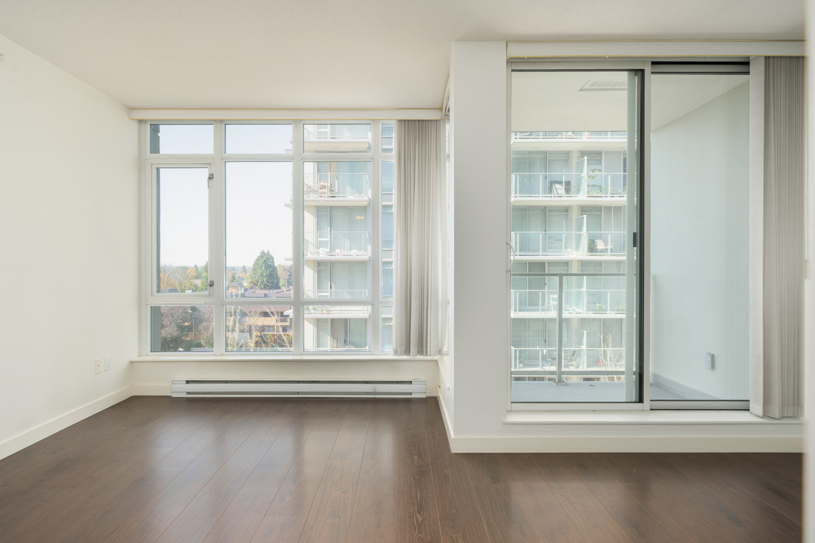 Empty room at 4818 Eldorado Mews featuring dark wood floors, floor-to-ceiling windows, and a sliding door to a balcony.