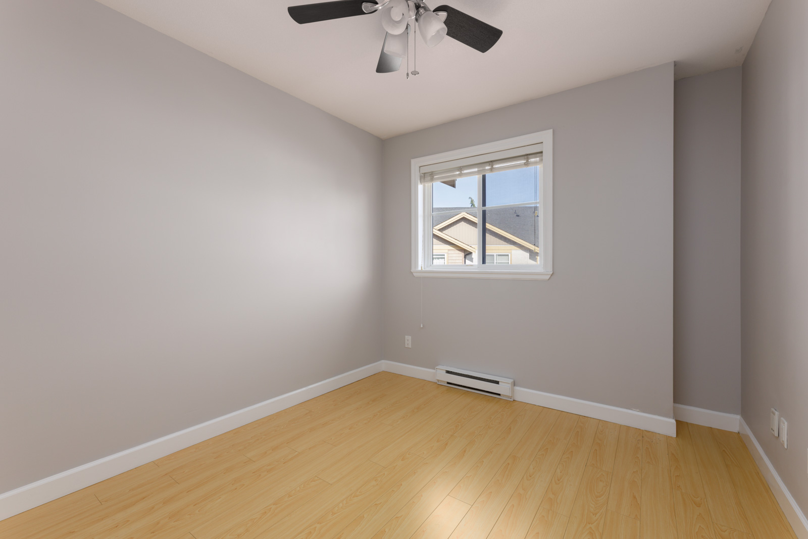 Empty room at 8633 159 Street featuring light wood-look flooring, light grey walls, a single window, and a ceiling fan.