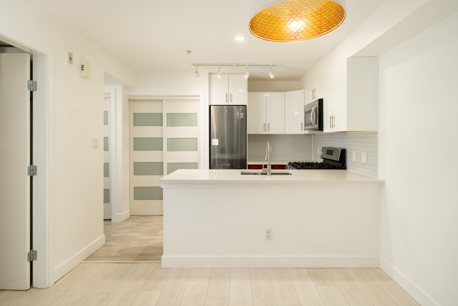 Modern kitchen at 9339 Alberta Rd with white cabinets, stainless steel appliances, and a peninsula island.