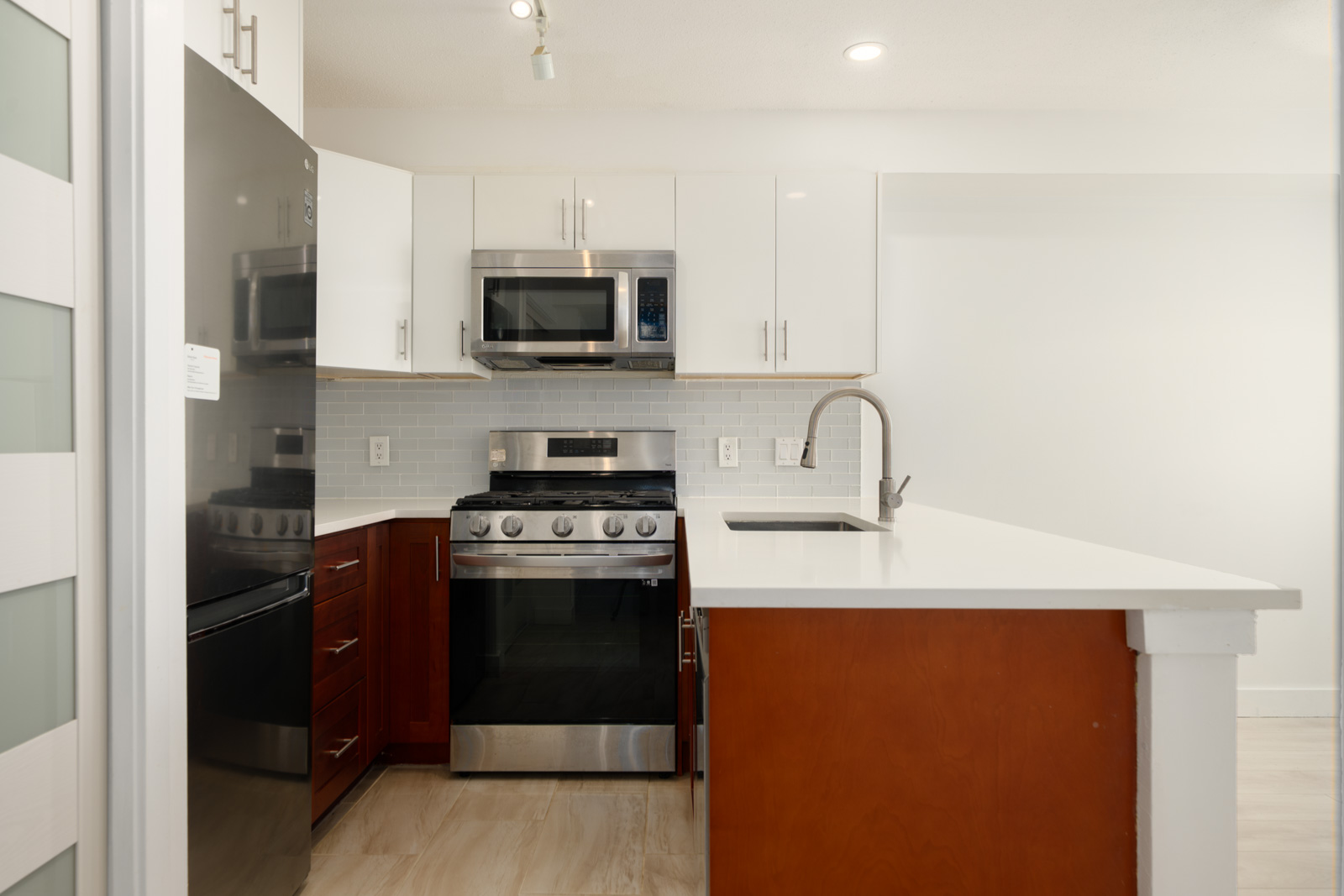 Richmond townhouse kitchen with white upper cabinets, dark wood lower cabinets, stainless steel appliances, and an island.