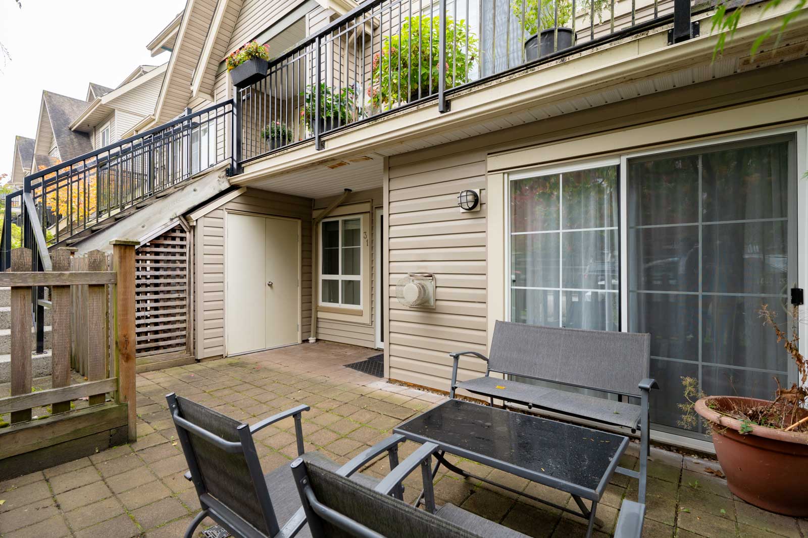 Paved patio at 9339 Alberta Rd, Richmond, with a small table and two chairs beneath an upper-level balcony.