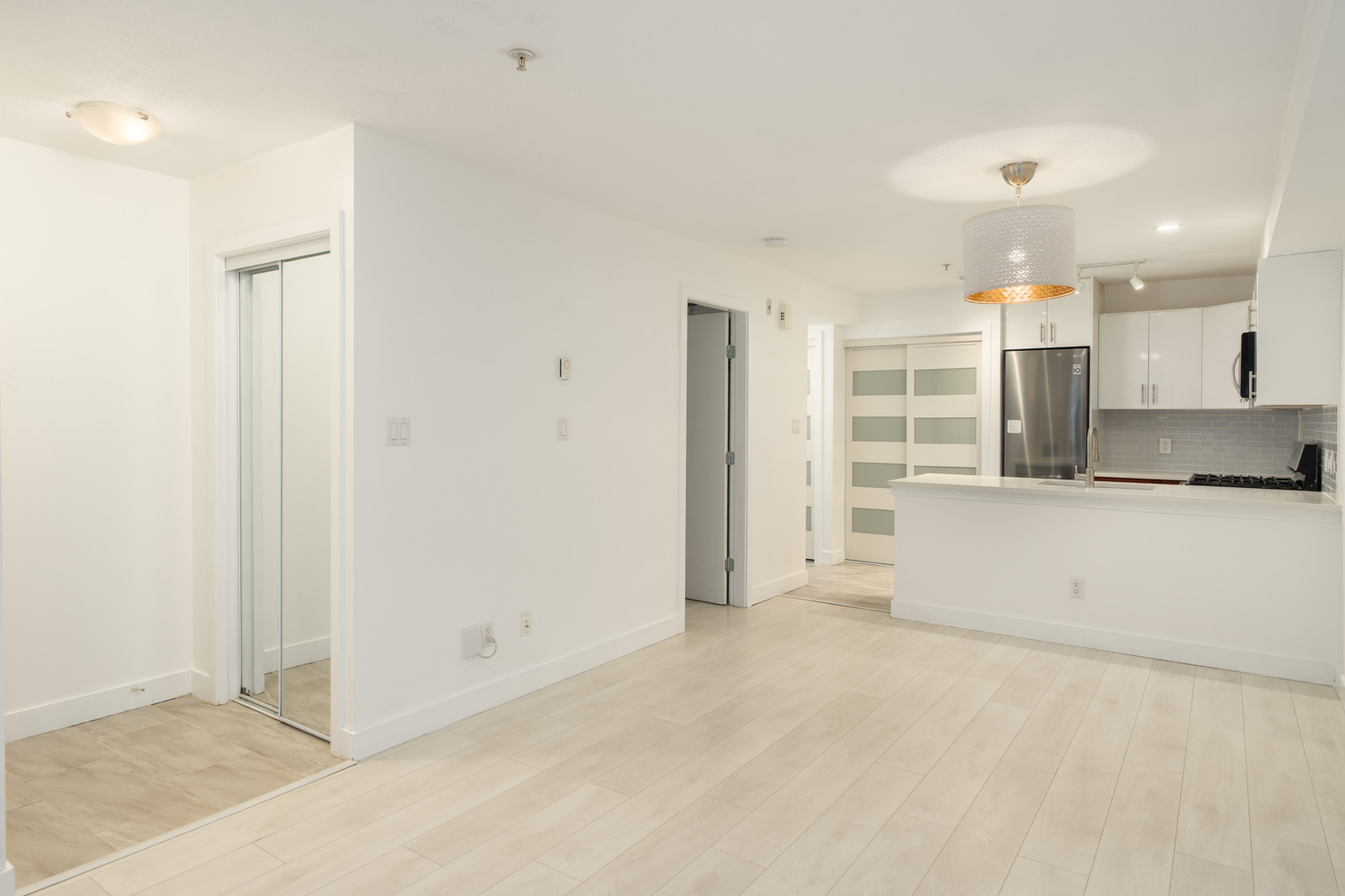 Open-plan Richmond townhouse interior with white walls, light wood flooring, and a kitchen with white cabinetry.