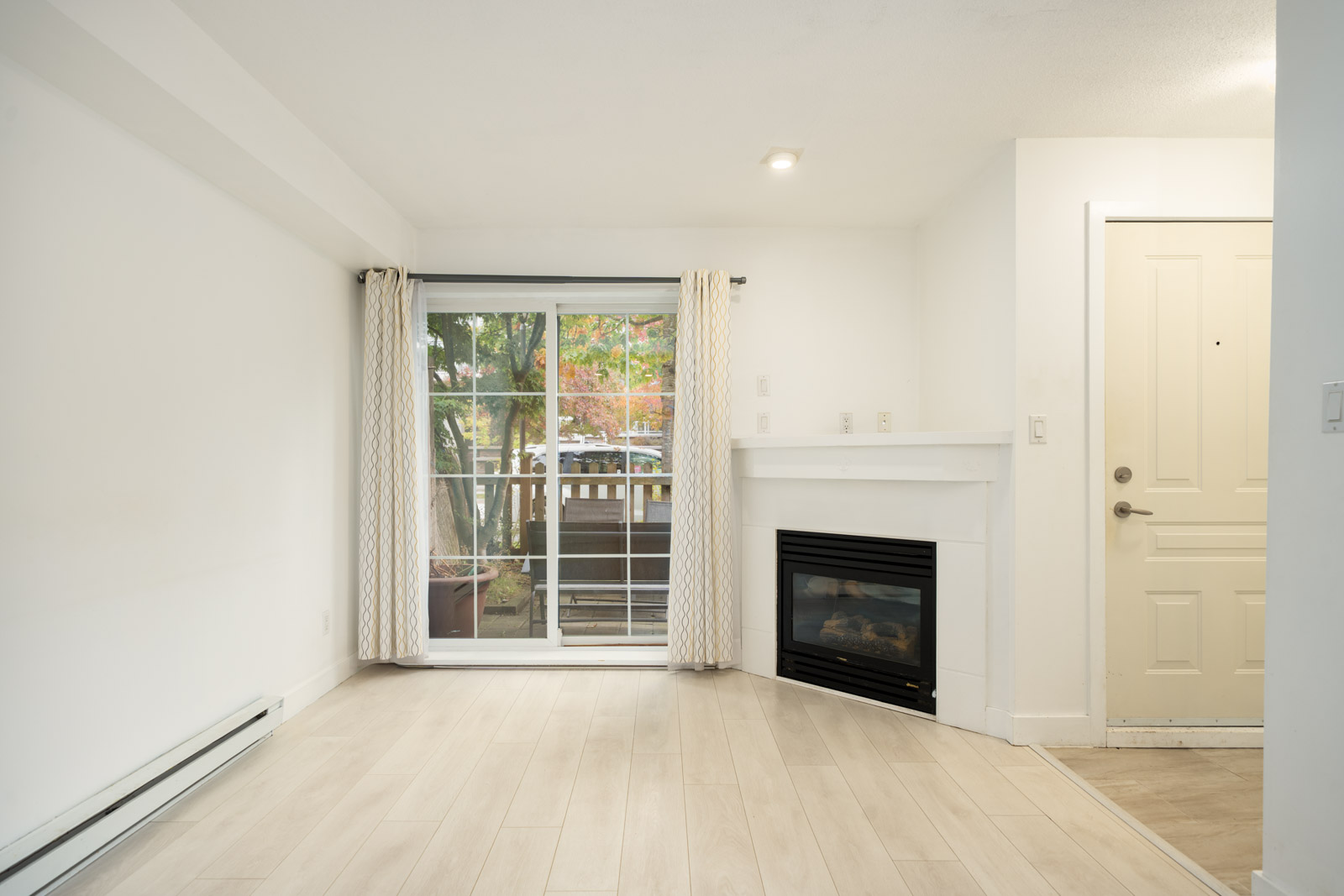 Living room with light floors, a corner fireplace, and patio sliding doors in a 9339 Alberta Rd, Richmond townhouse.