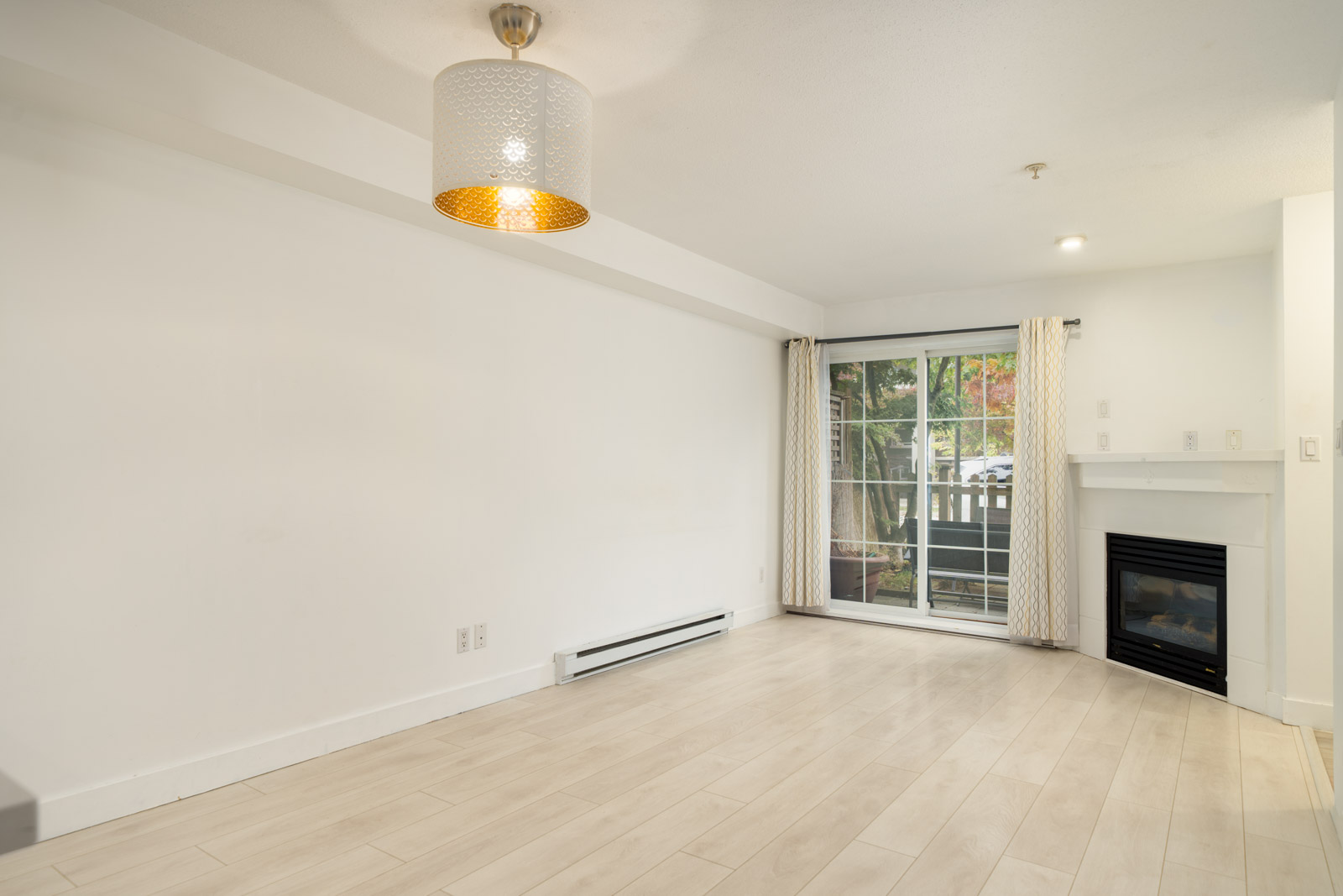 Living room in a 9339 Alberta Rd Richmond townhouse with light flooring, a corner fireplace, and a sliding glass door.
