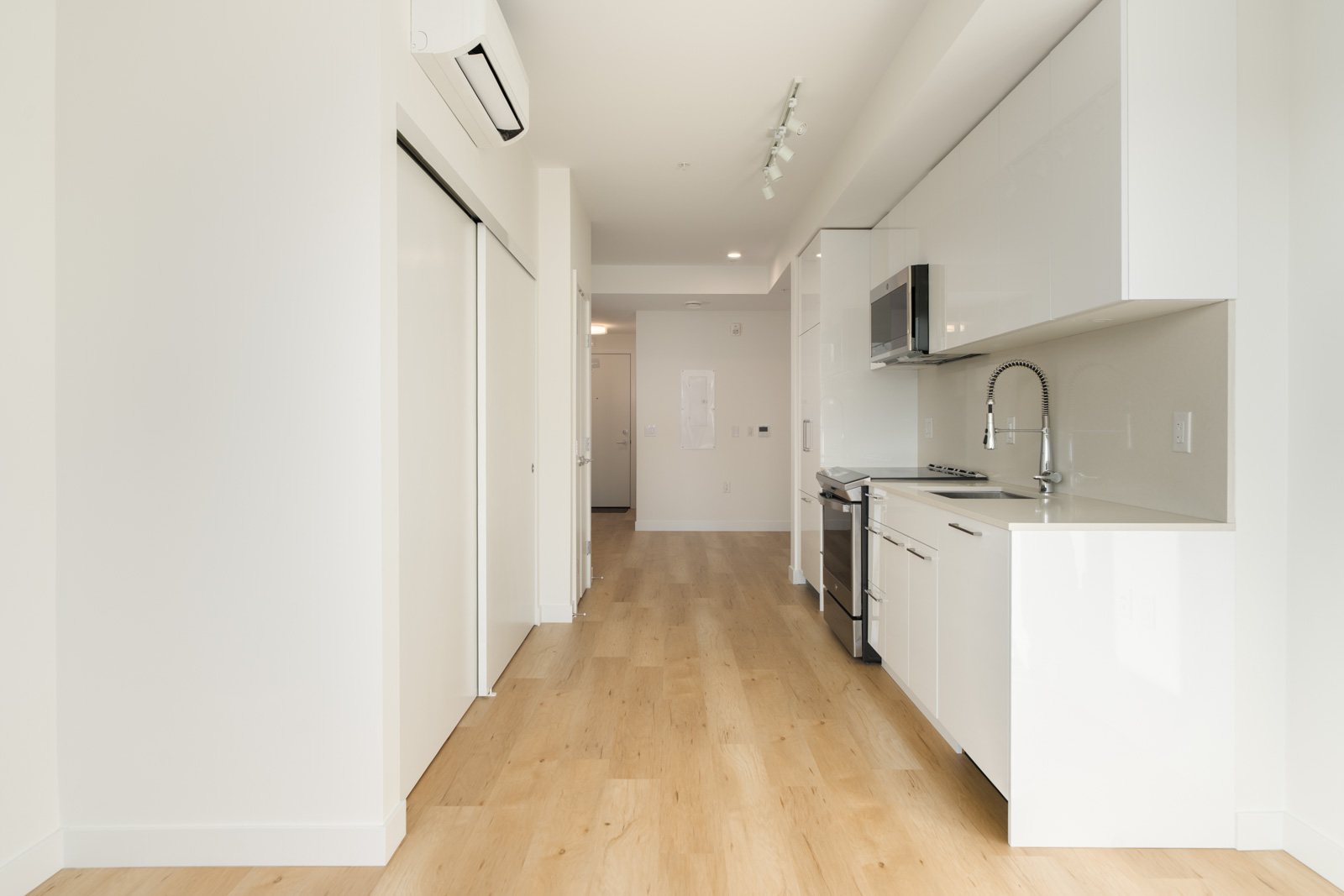 Modern kitchen with white cabinets, stainless steel appliances, and wood floors, seen from a 2nd-floor Port Coquitlam home.