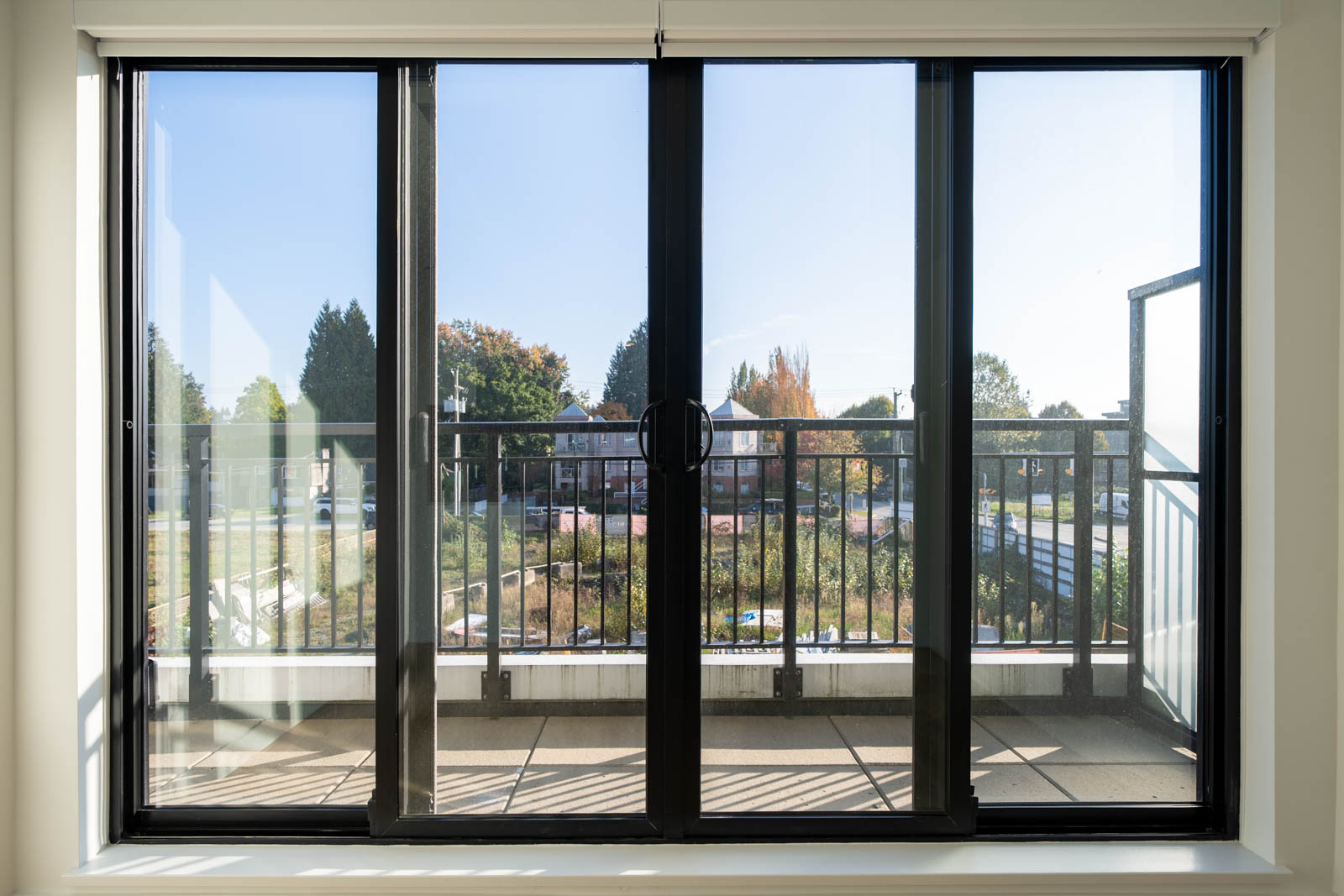 Sliding glass doors in a 2nd-floor Shaughnessy St office open to a balcony overlooking a street and neighborhood trees.