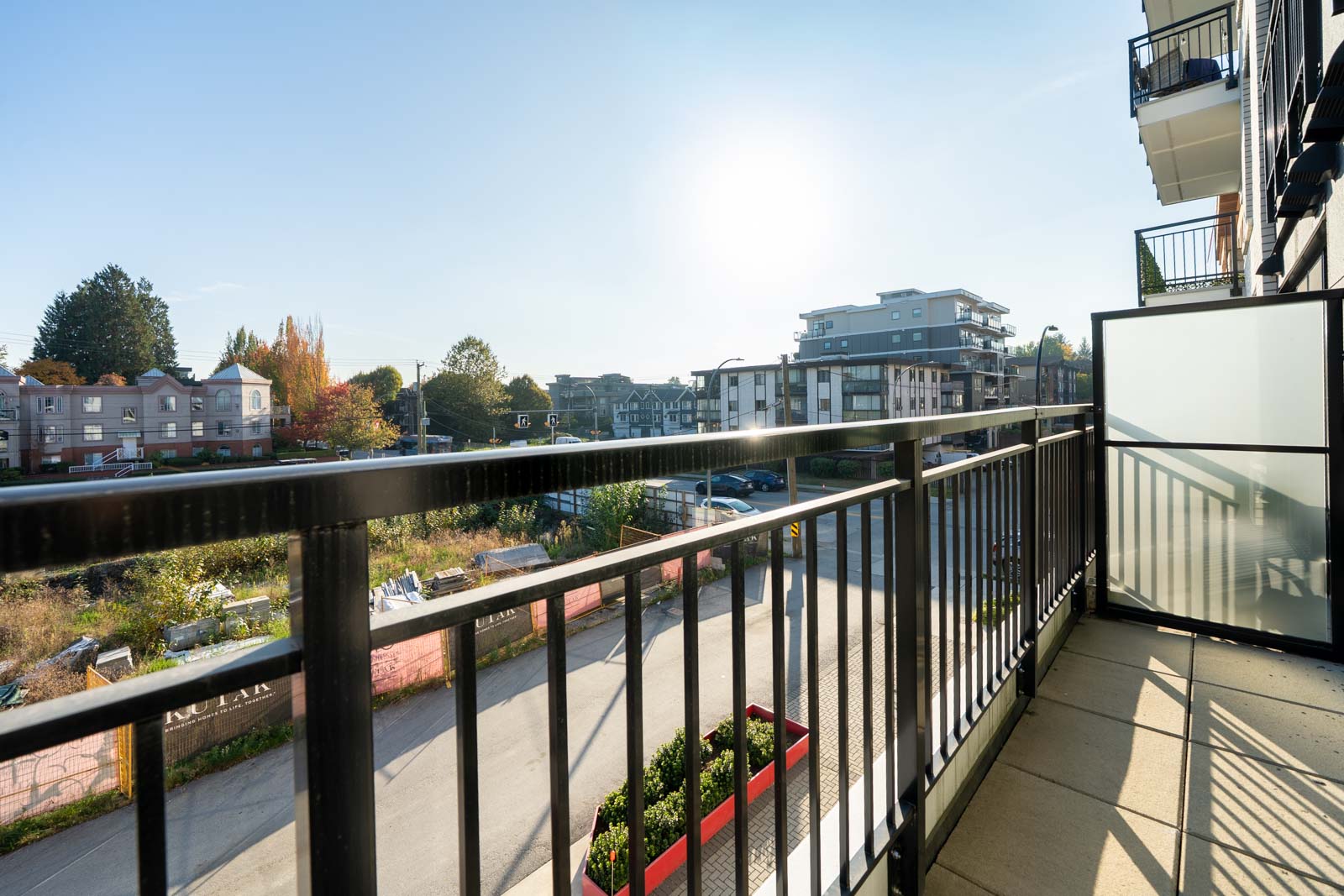 View from a 2nd-floor balcony on Shaughnessy St overlooking a city street and nearby low-rise apartment buildings.