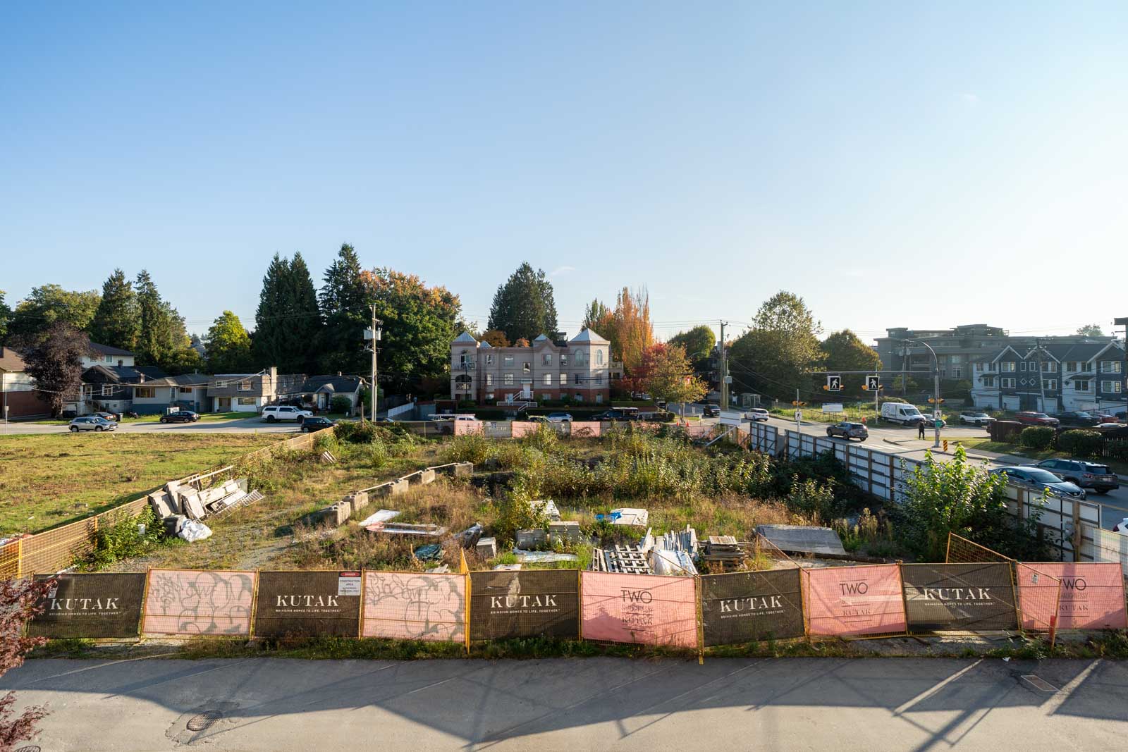 Fenced-in construction lot with debris near 2446 Shaughnessy St, surrounded by trees and residential buildings.