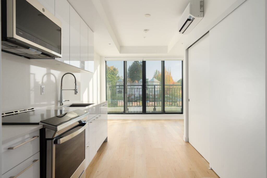 Modern kitchen at 2446 Shaughnessy St, Port Coquitlam, with white cabinetry, stainless appliances, and a treed balcony.